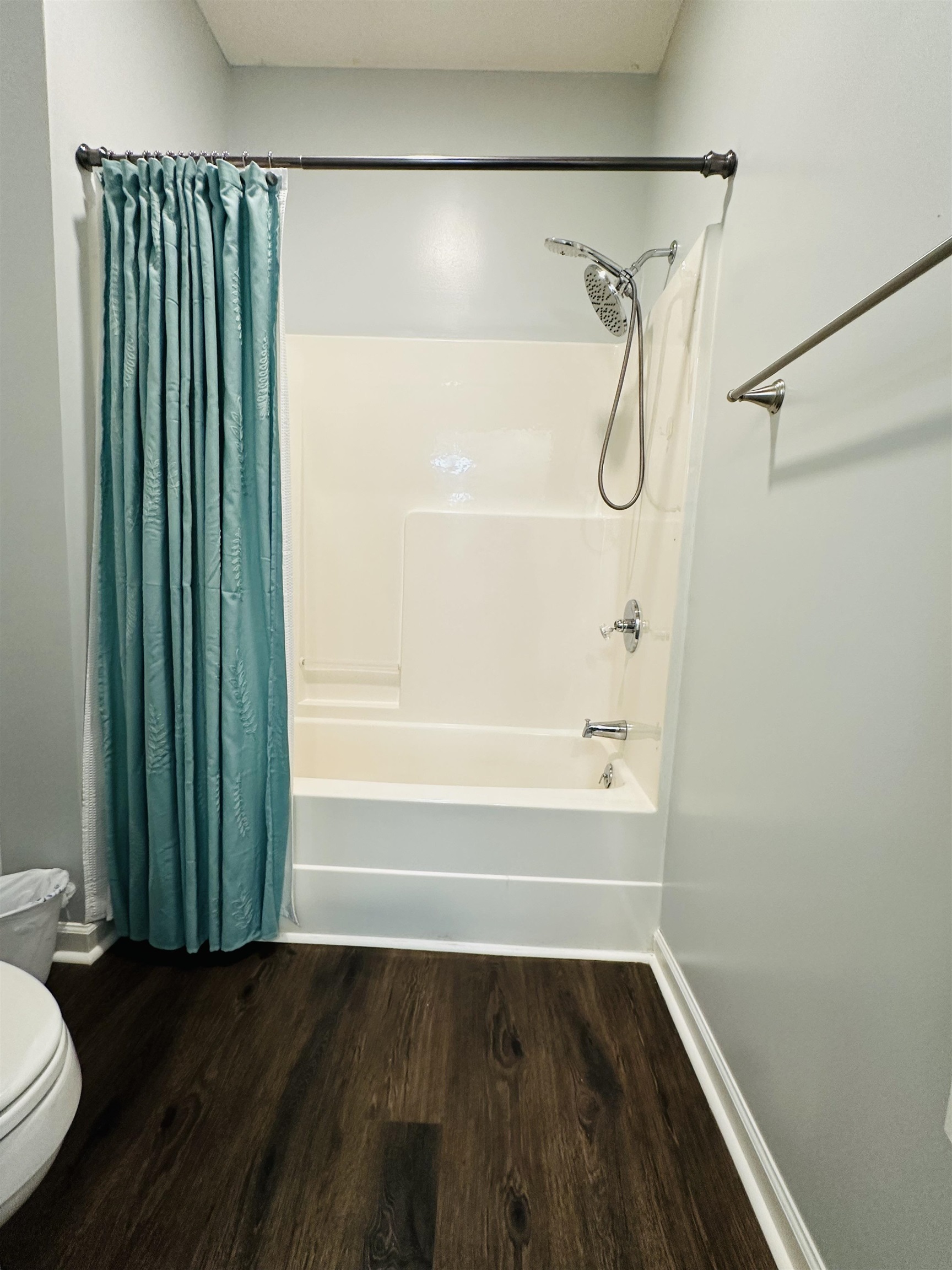 Bathroom featuring hardwood / wood-style flooring, toilet, and shower / bath combo