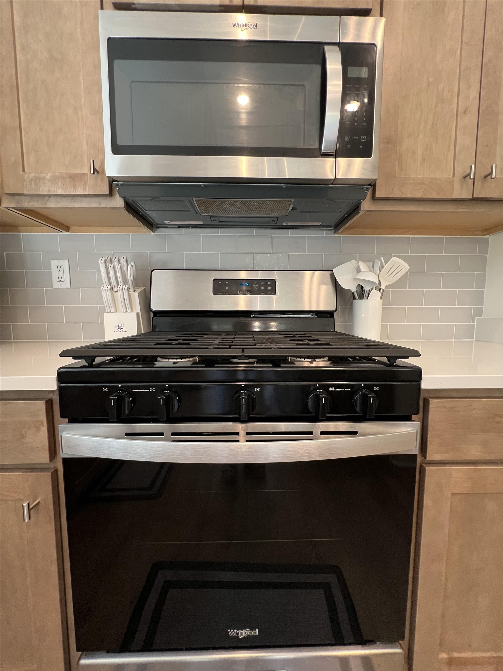 Kitchen featuring stainless steel appliances, light brown cabinets, and tasteful backsplash