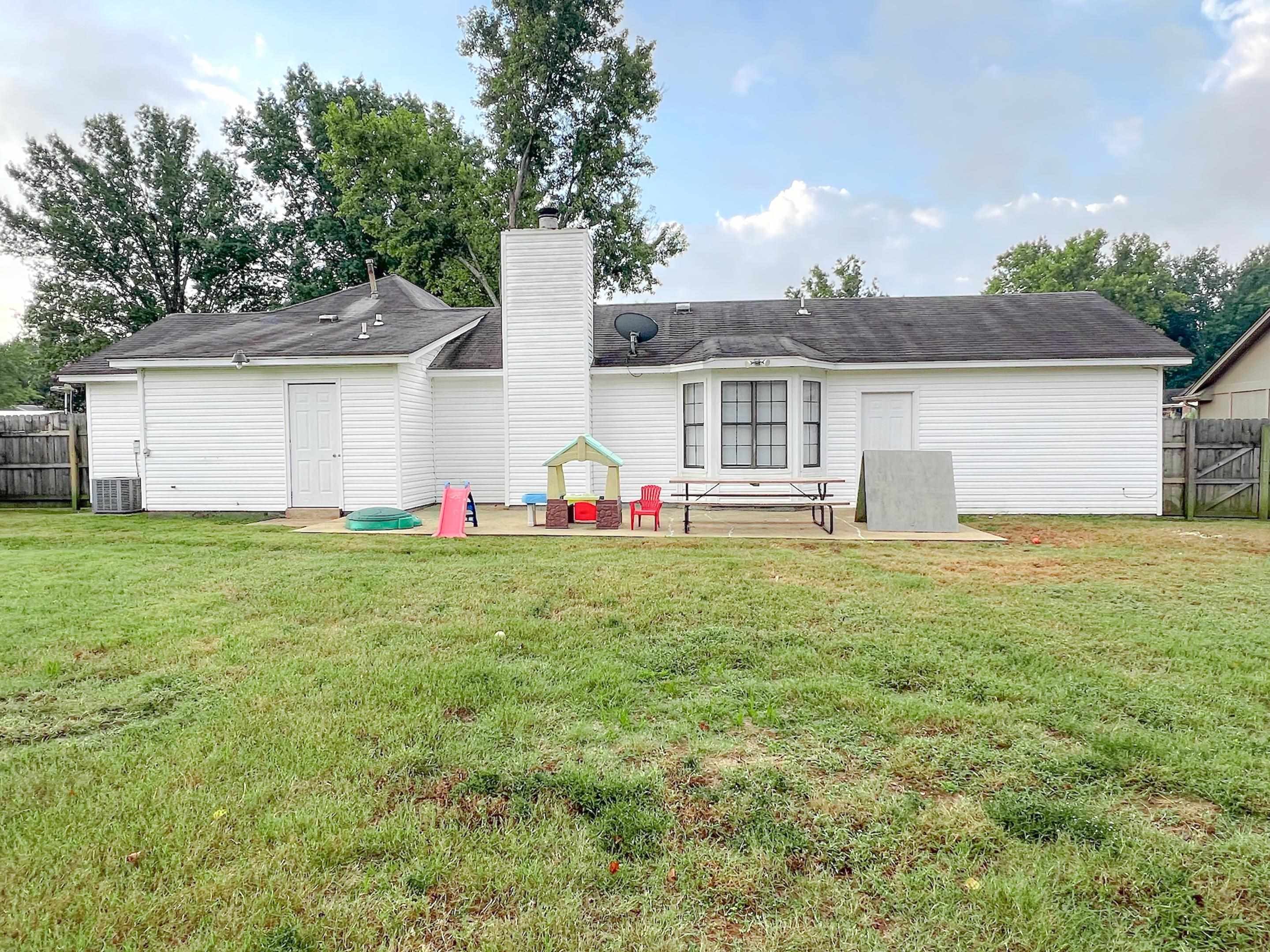 Rear view of property featuring a lawn, cooling unit, and a patio