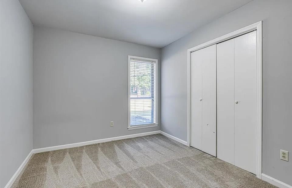 Unfurnished bedroom with light carpet and a closet