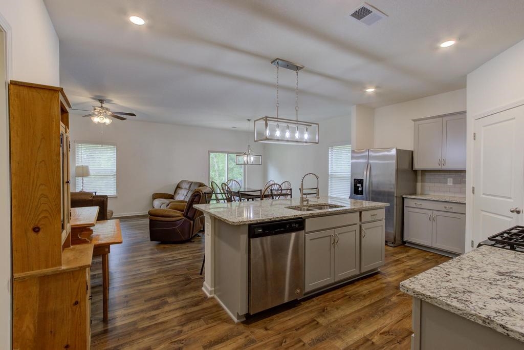 Kitchen with ceiling fan, pendant lighting, sink, a center island with sink, and appliances with stainless steel finishes