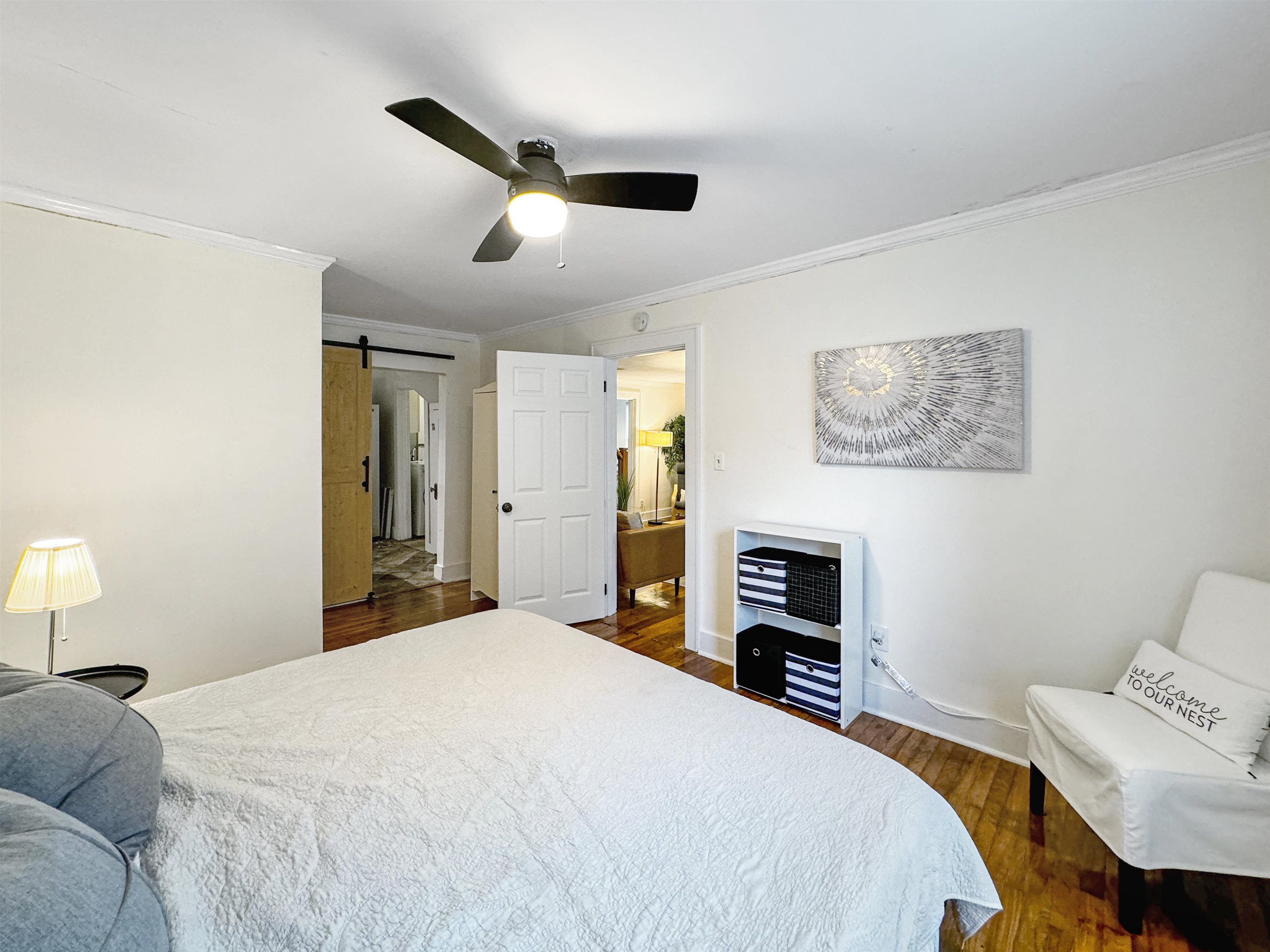 Bedroom with ceiling fan, ornamental molding, dark hardwood / wood-style floors, and a barn door
