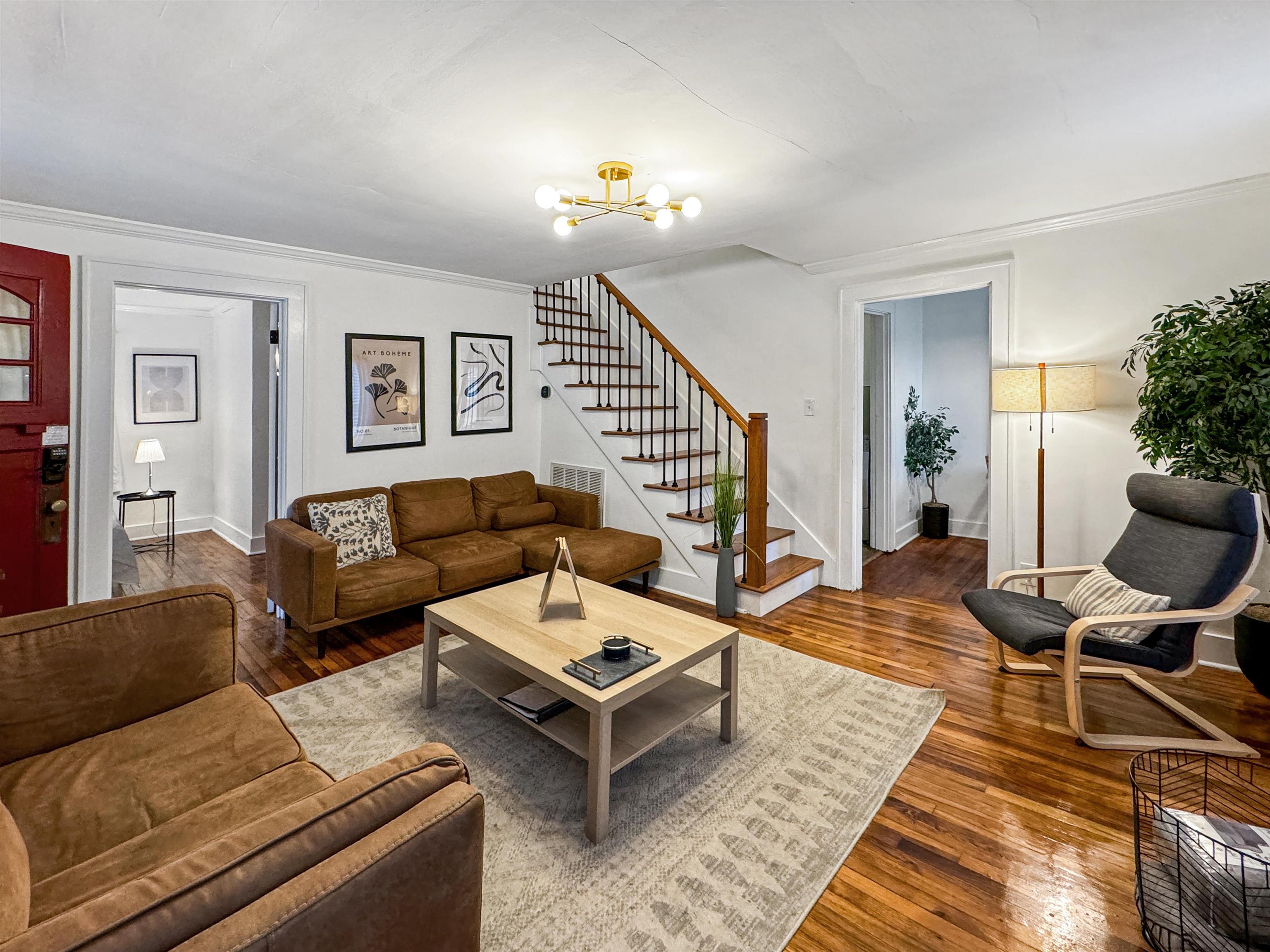 Living room with ornamental molding, hardwood / wood-style flooring, and a notable chandelier