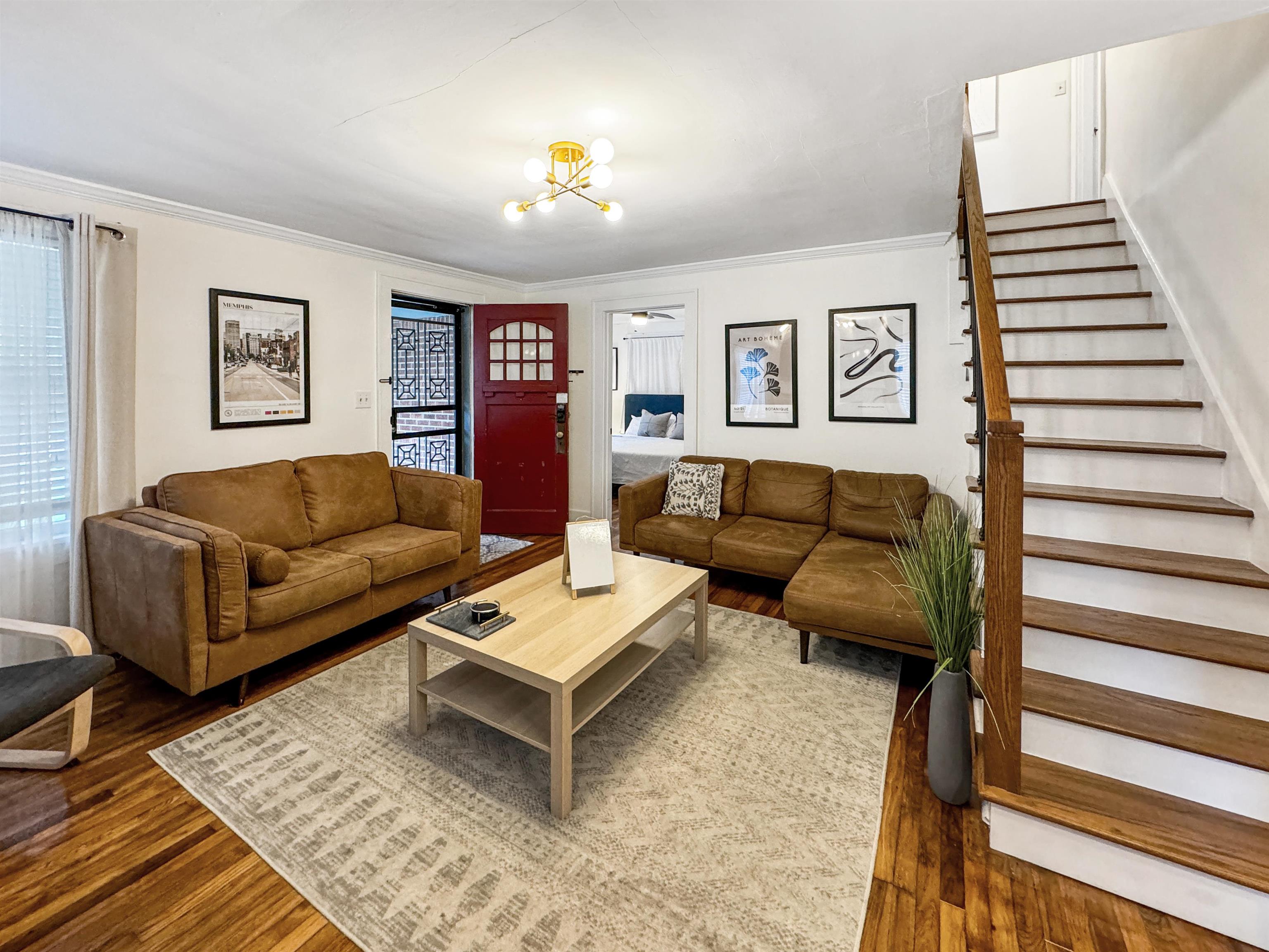 Living room with an inviting chandelier, ornamental molding, and dark hardwood / wood-style flooring