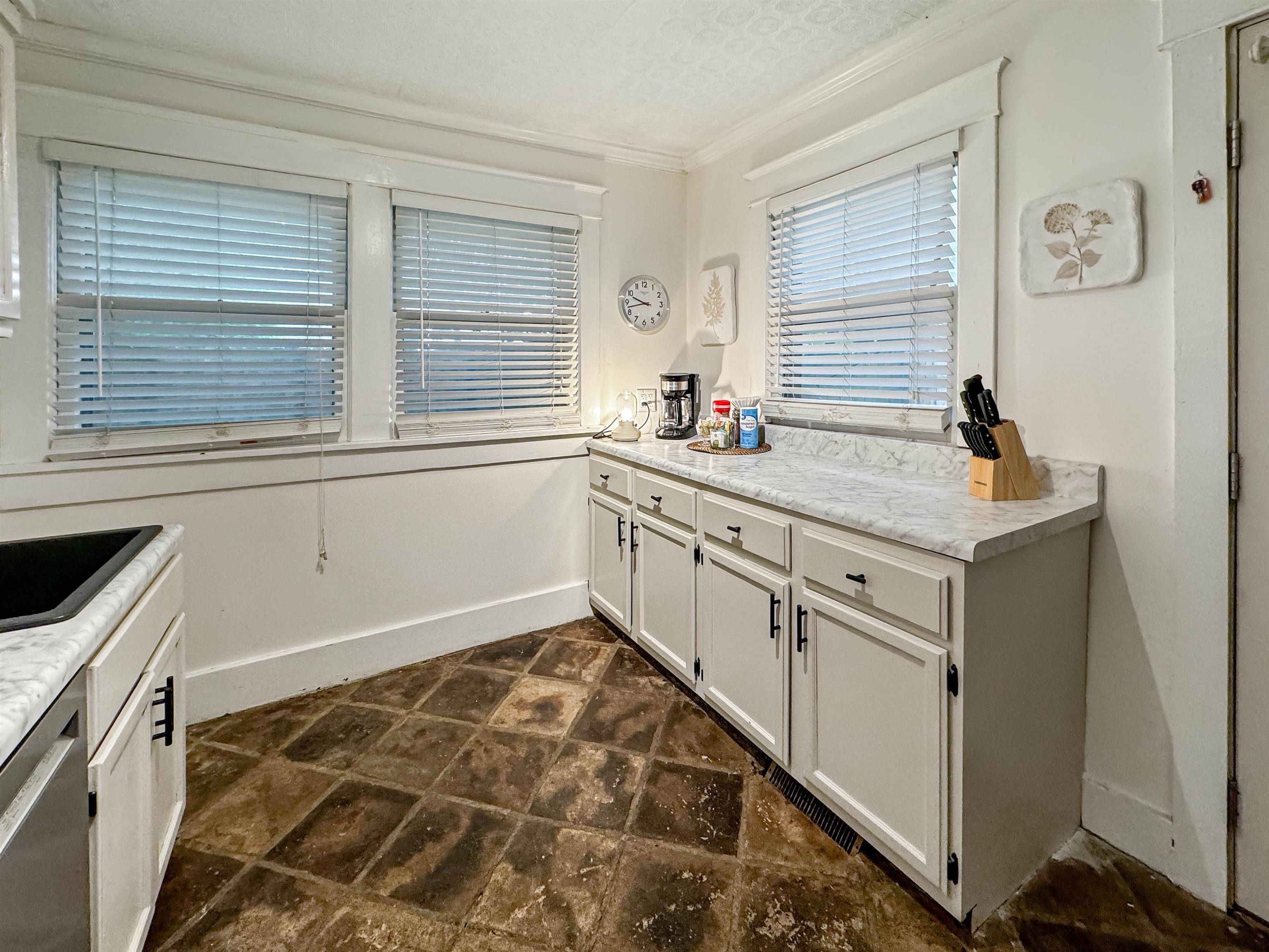 Kitchen featuring a textured ceiling, sink, white cabinetry, crown molding, and stainless steel dishwasher