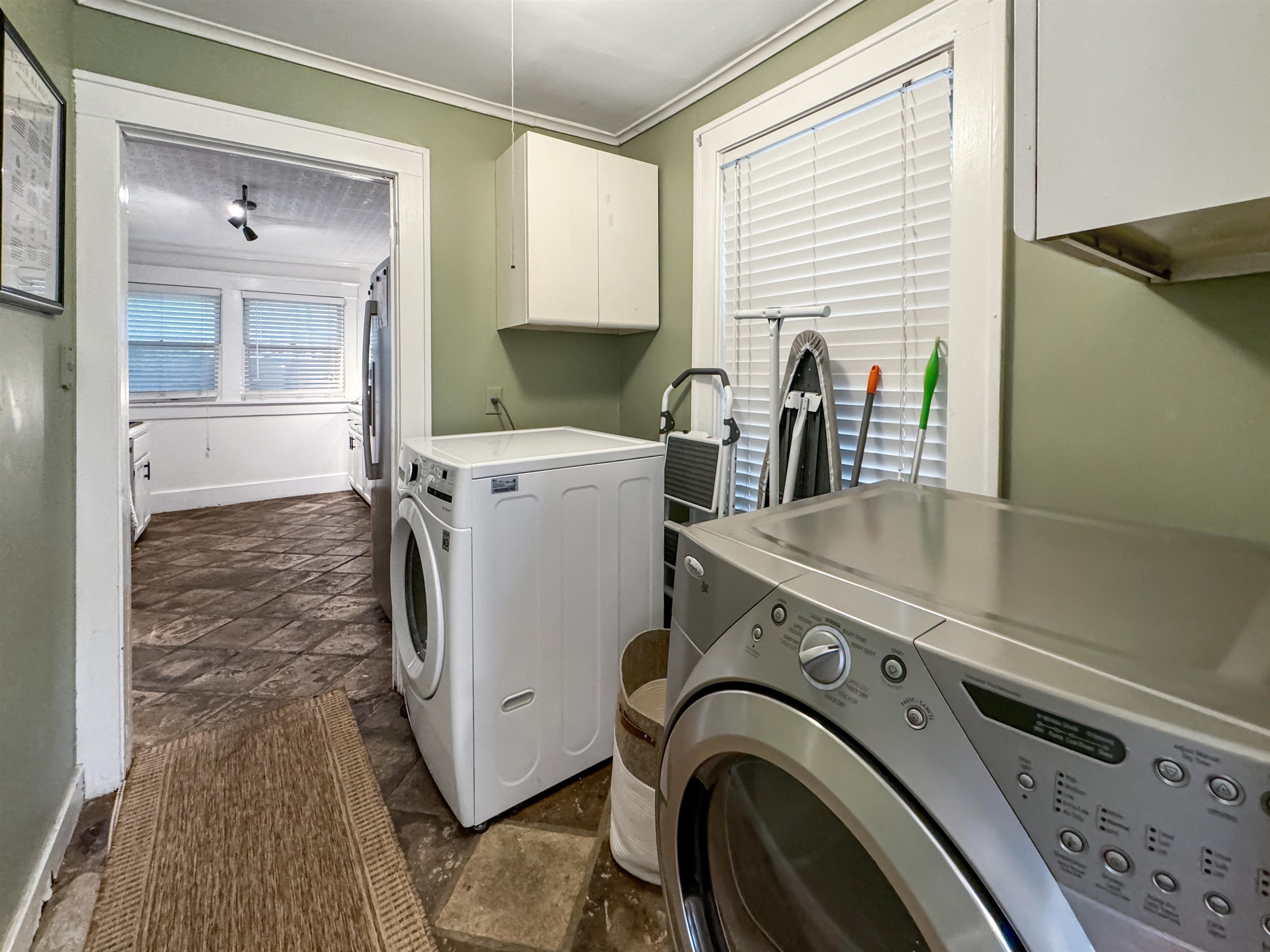 Washroom featuring ornamental molding, independent washer and dryer, and cabinets