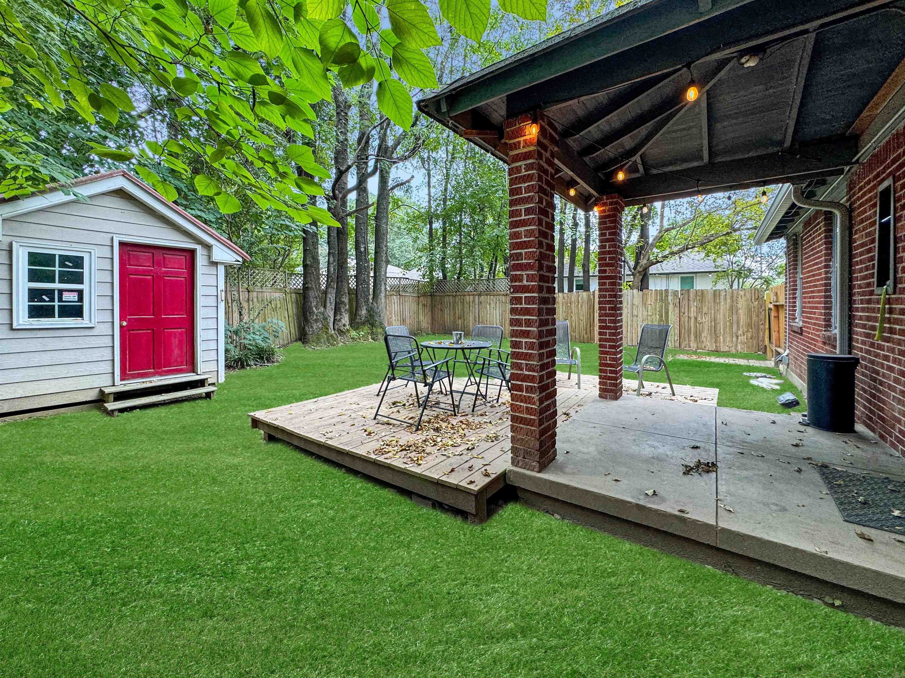 Wooden terrace with a storage shed, a yard, and a patio area