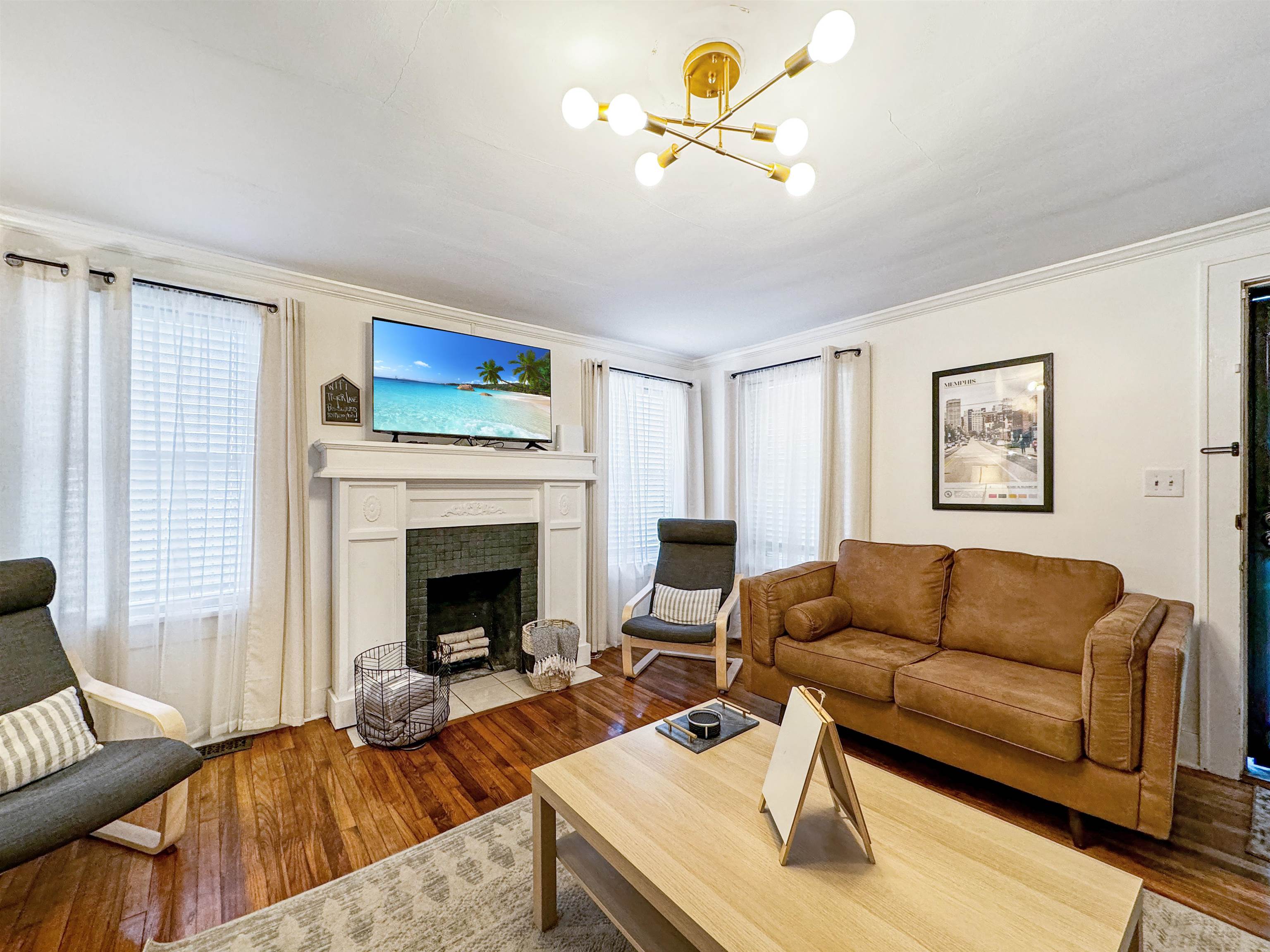 Living room with a tile fireplace, plenty of natural light, an inviting chandelier, and hardwood / wood-style flooring