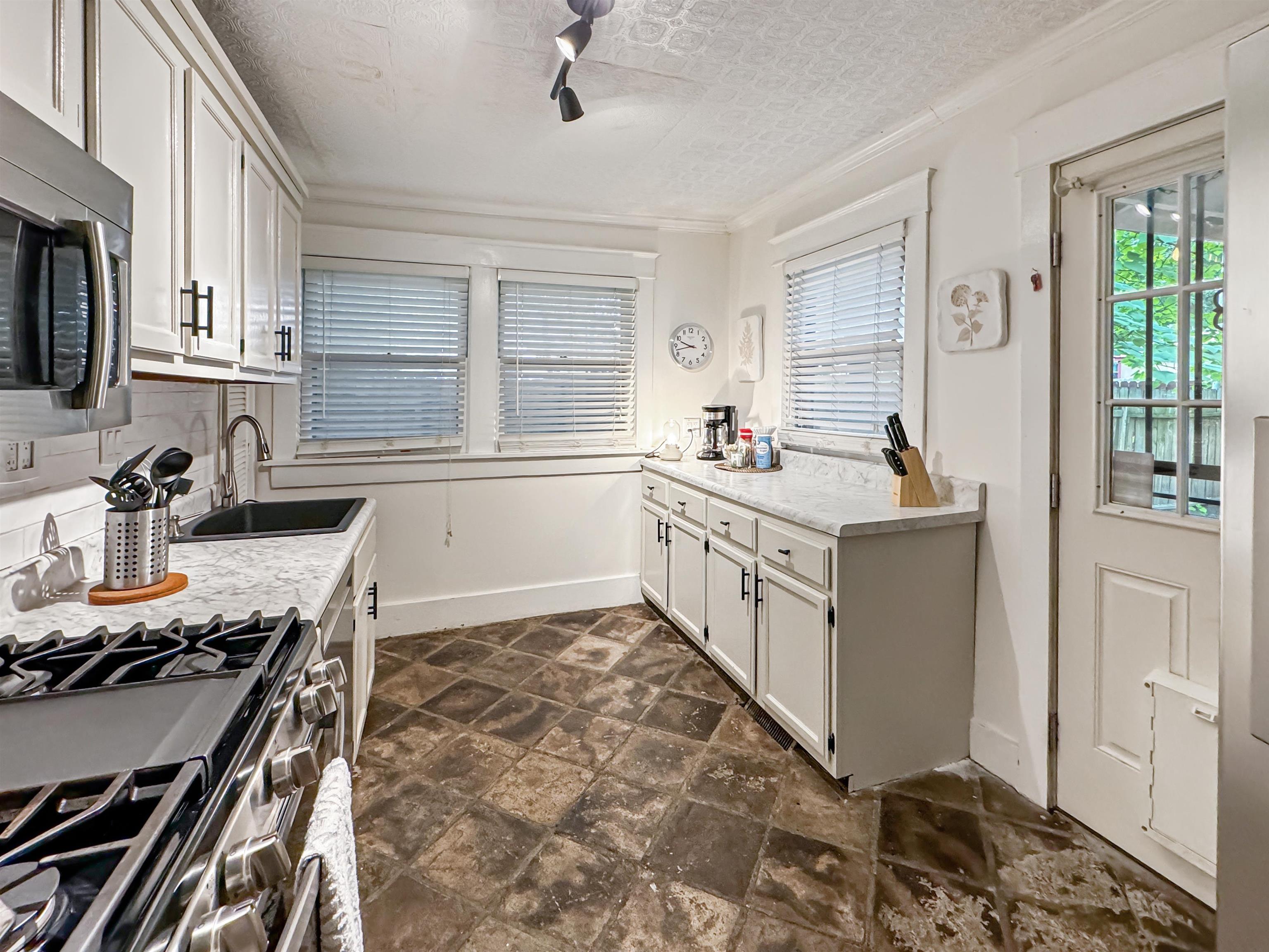 Kitchen with stainless steel appliances, white cabinets, a healthy amount of sunlight, and sink