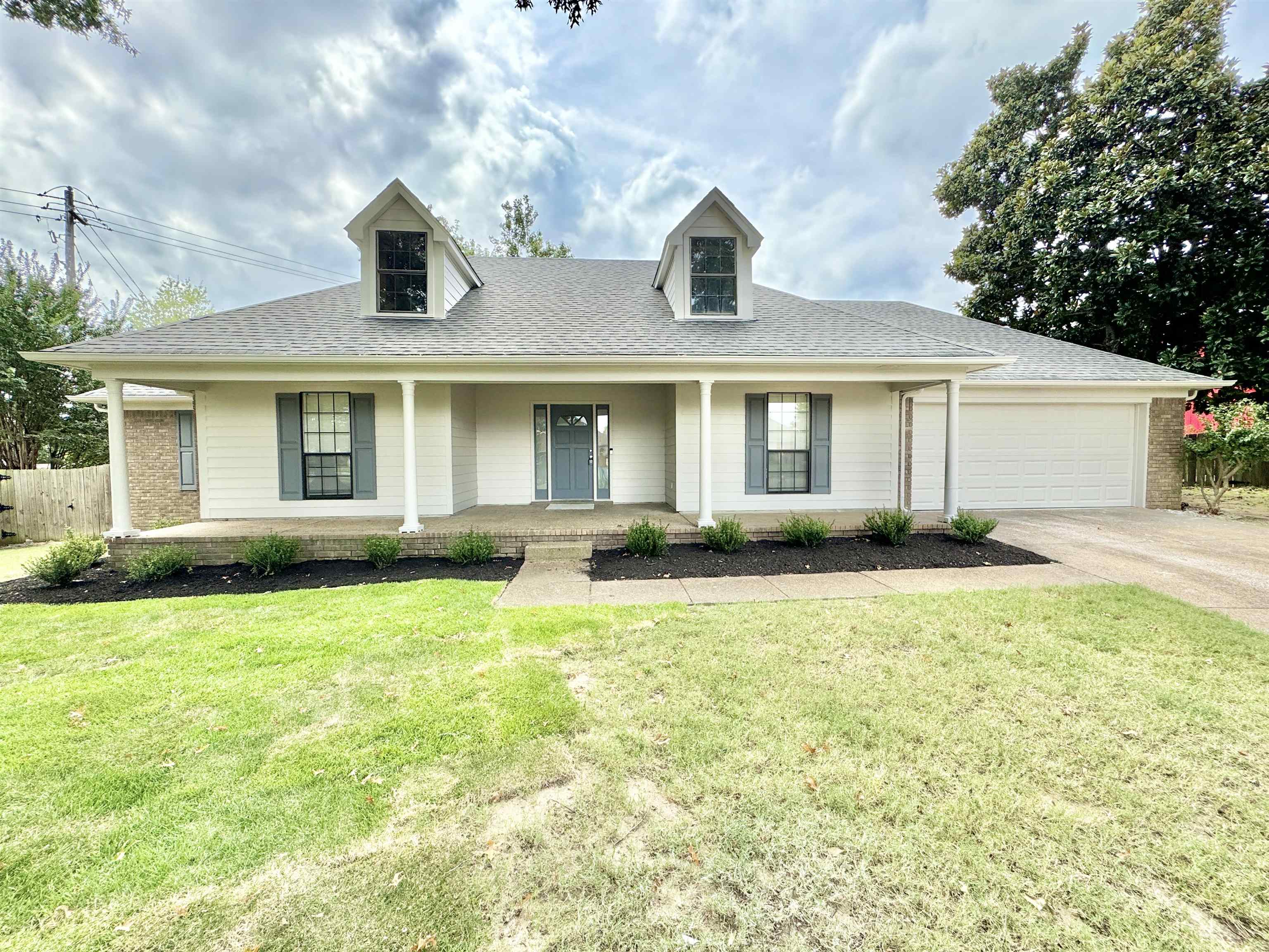 View of front of home featuring a front yard, a garage, and a porch