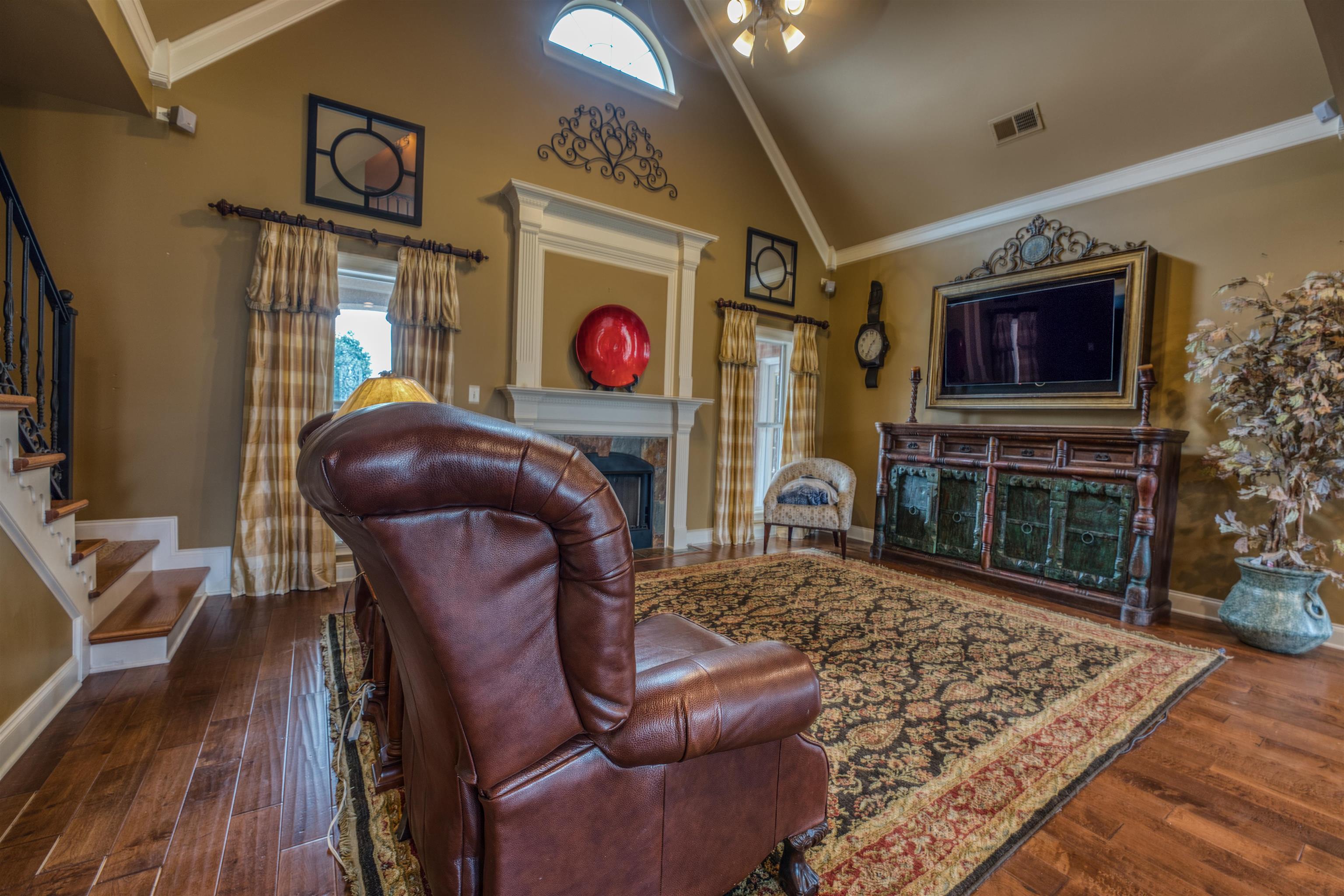 Living room featuring ornamental molding, high vaulted ceiling, and dark wood-type flooring