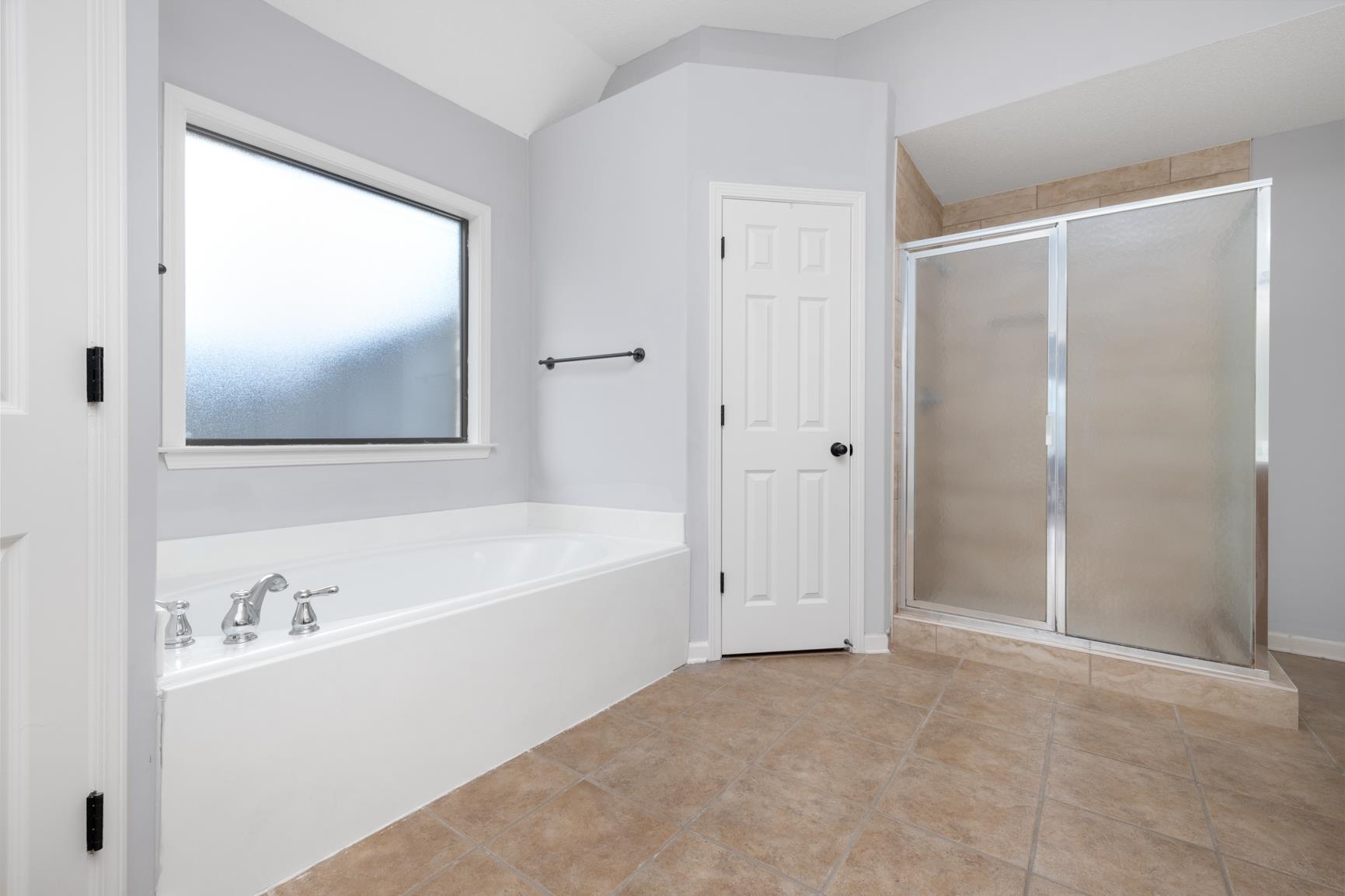 Bathroom with vaulted ceiling, separate shower and tub, and tile patterned floors