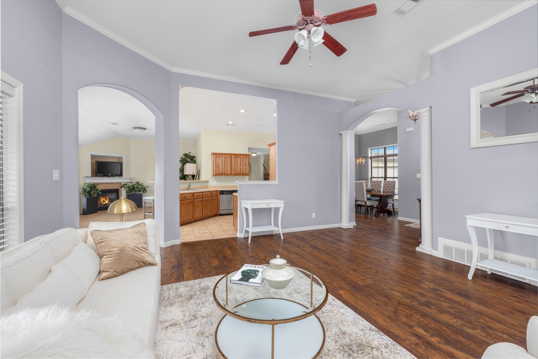 Living room featuring ceiling fan, lofted ceiling, ornamental molding, and wood-type flooring