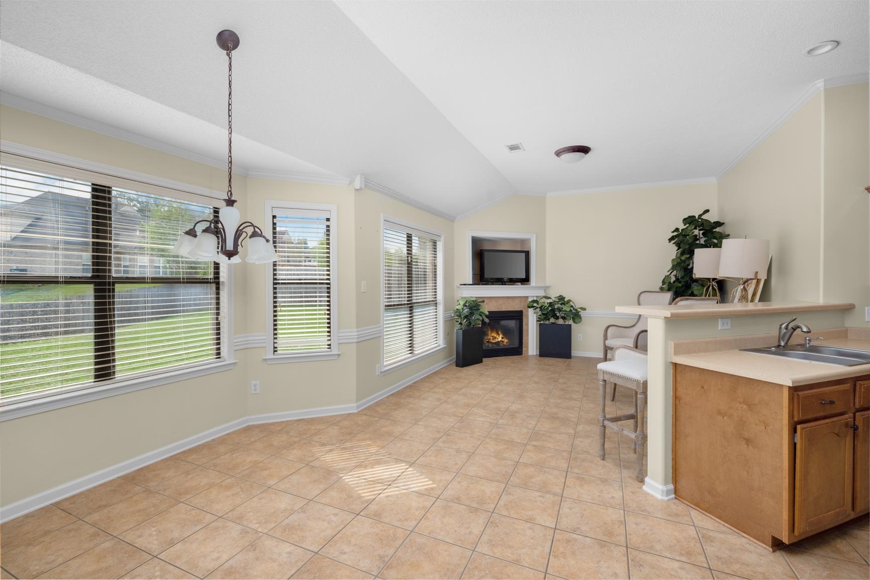 Kitchen featuring pendant lighting, light tile patterned flooring, sink, an inviting chandelier, and vaulted ceiling