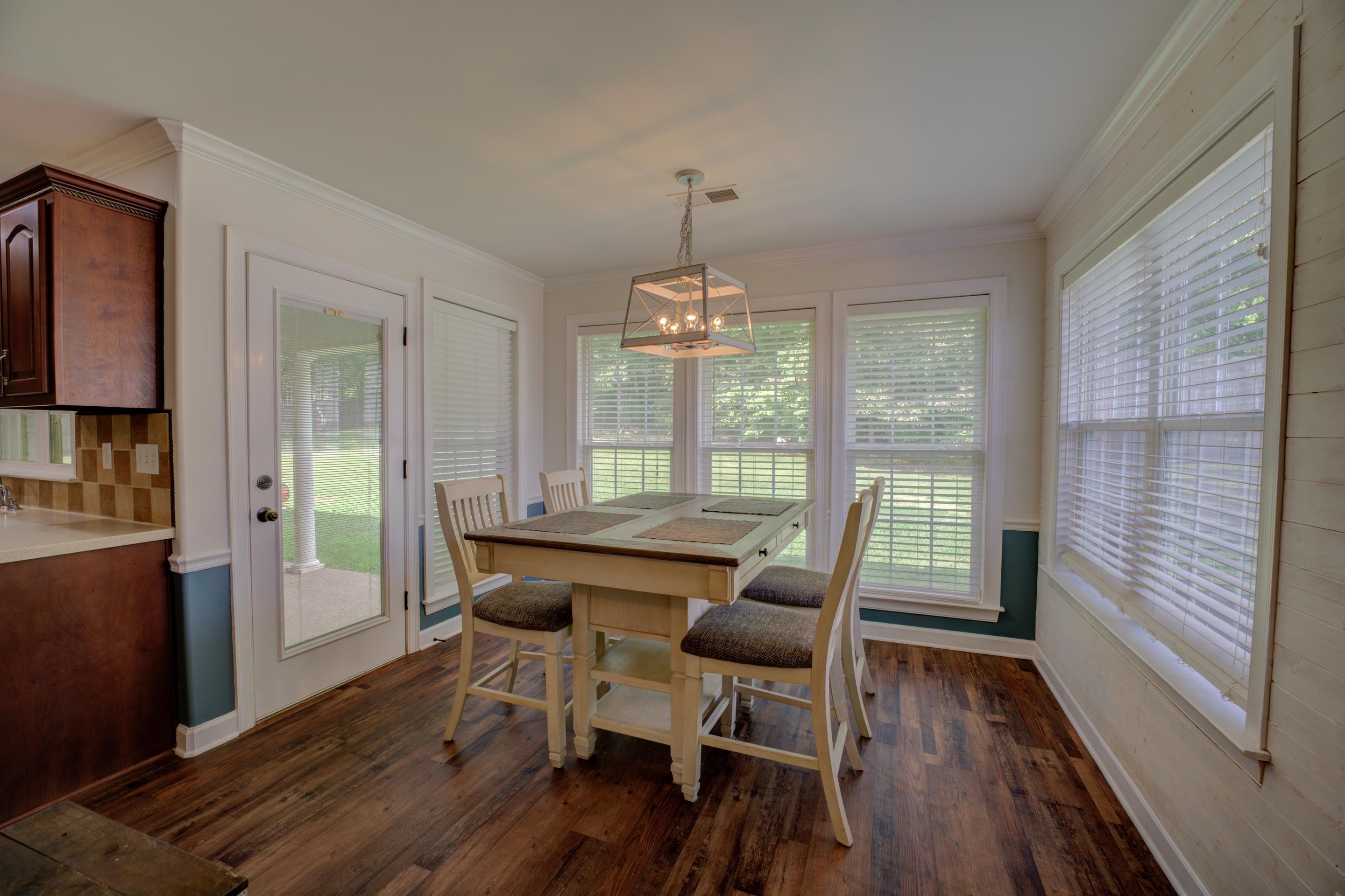 Sunny breakfast area with a chandelier, dark wood flooring, and crown molding.