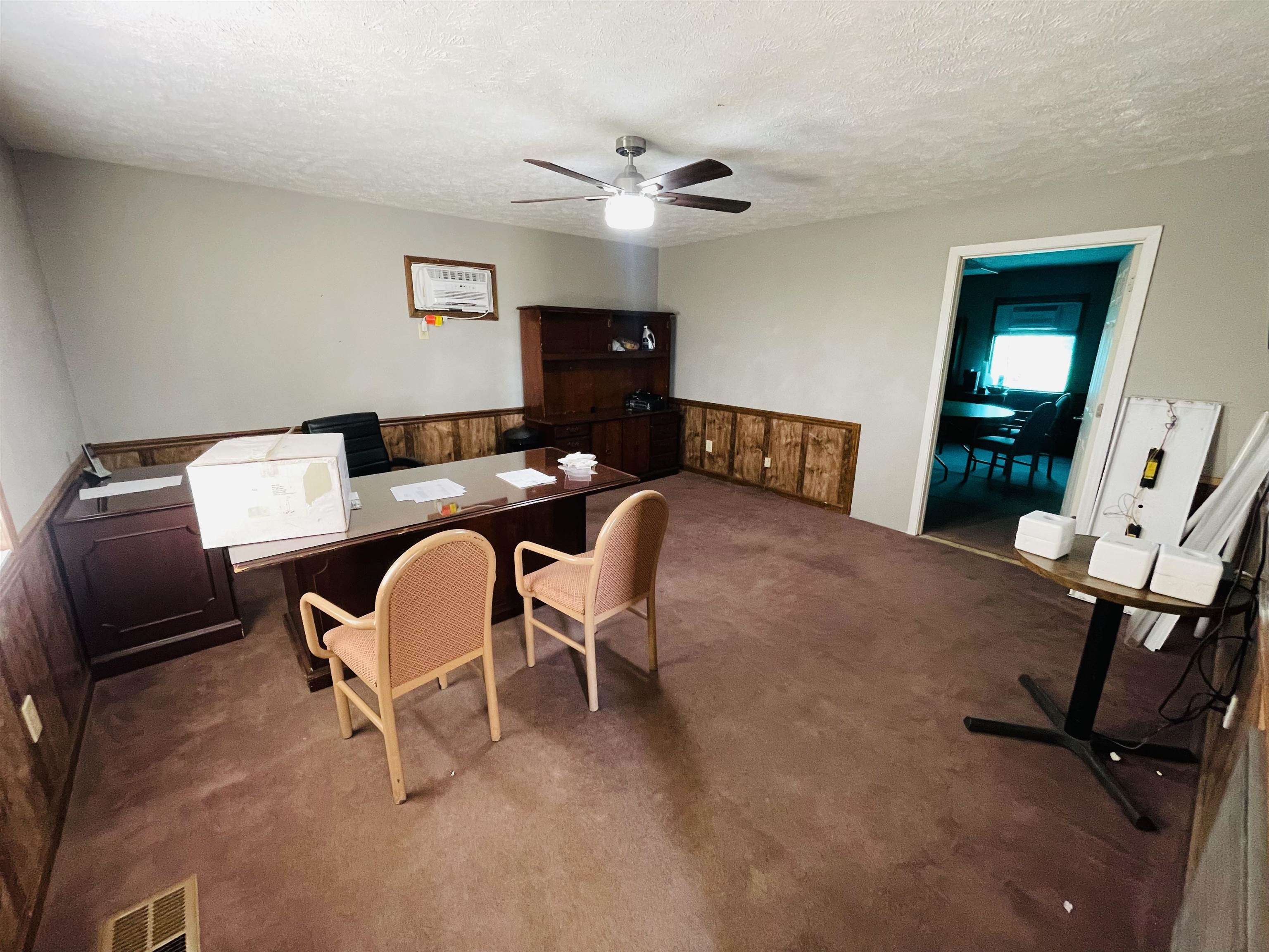 Carpeted home office featuring a textured ceiling and ceiling fan