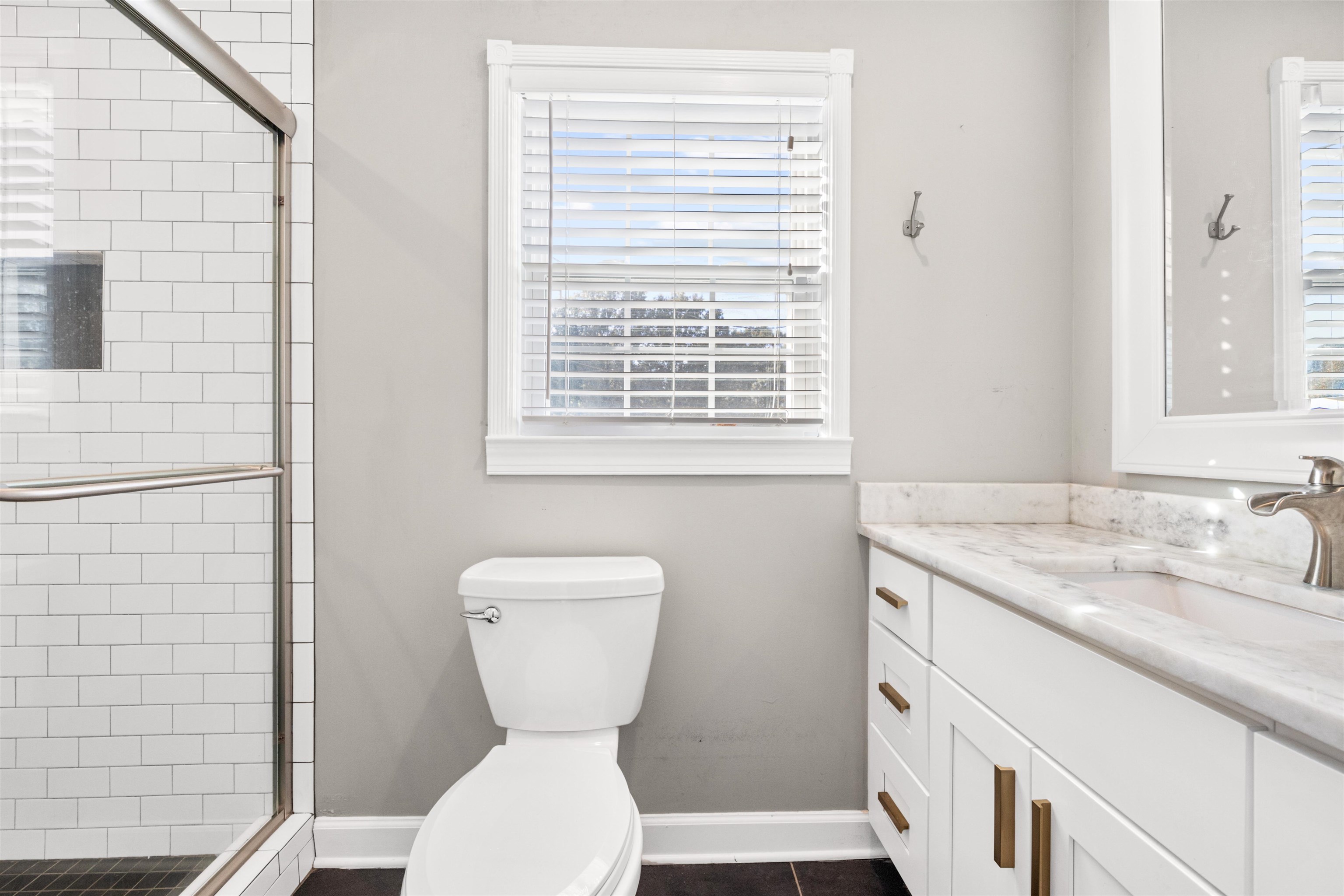 Bathroom with vanity, a shower with shower door, toilet, and tile patterned floors