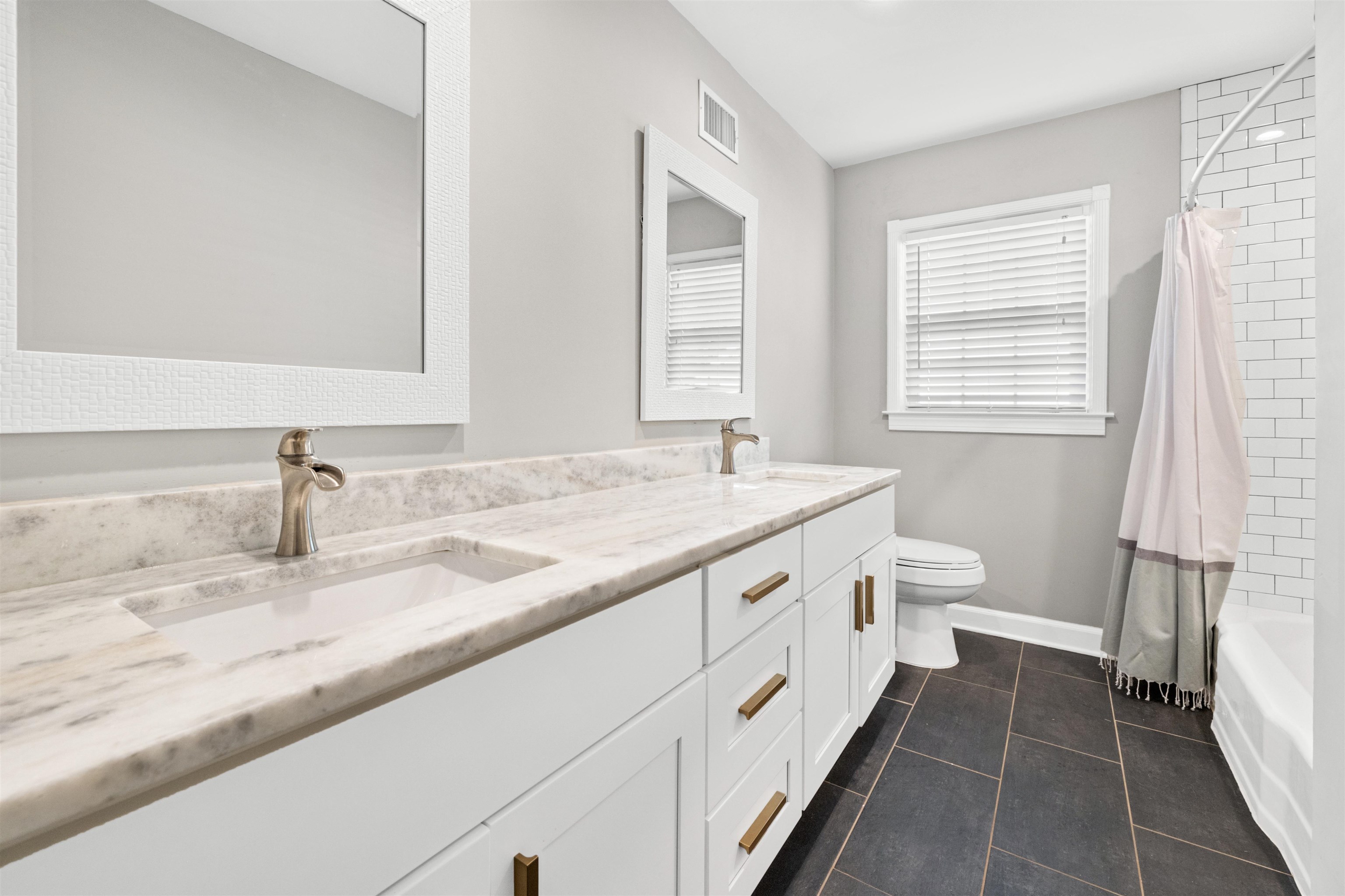 Full bathroom featuring shower / bath combo with shower curtain, tile patterned floors, vanity, and toilet