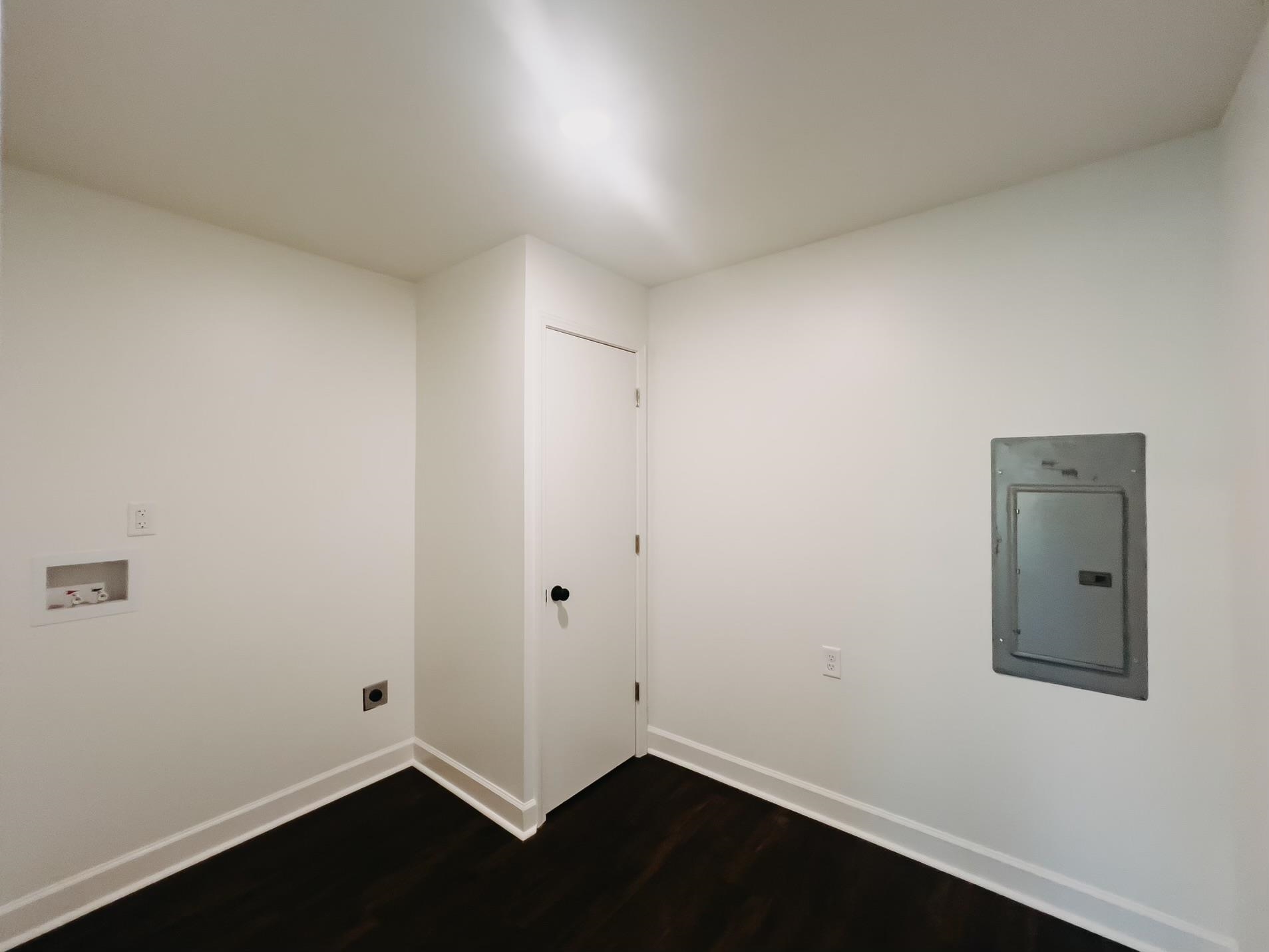 Clothes washing area with electric dryer hookup, electric panel, dark wood-type flooring, and hookup for a washing machine