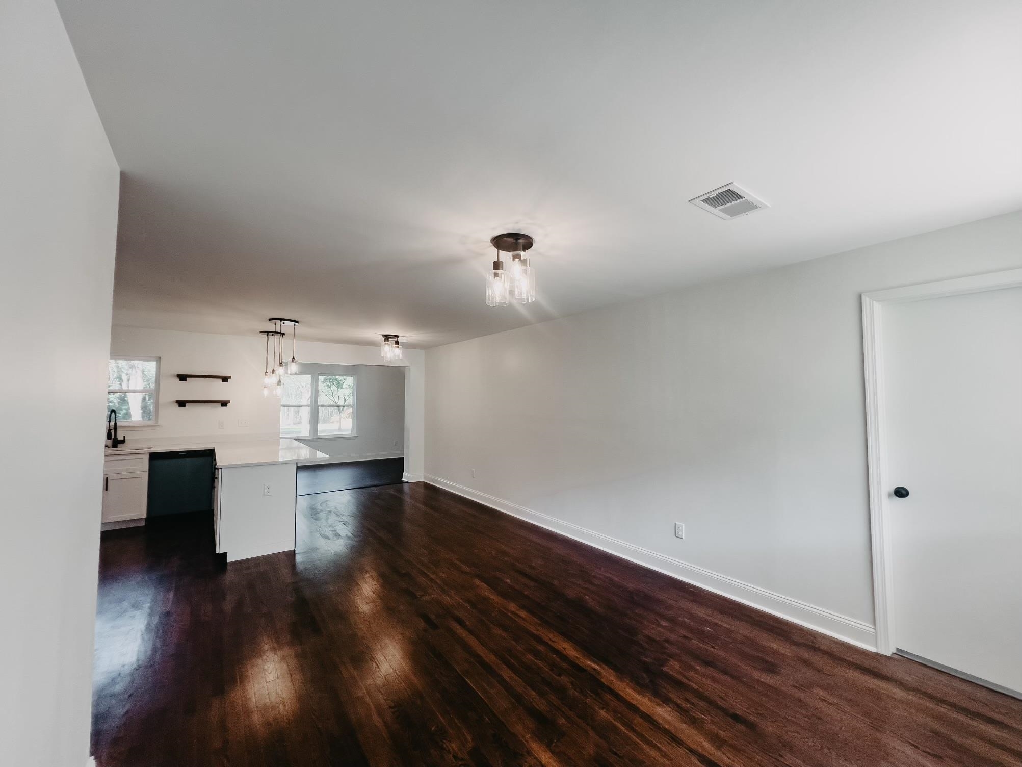 Unfurnished living room with sink and dark wood-type flooring