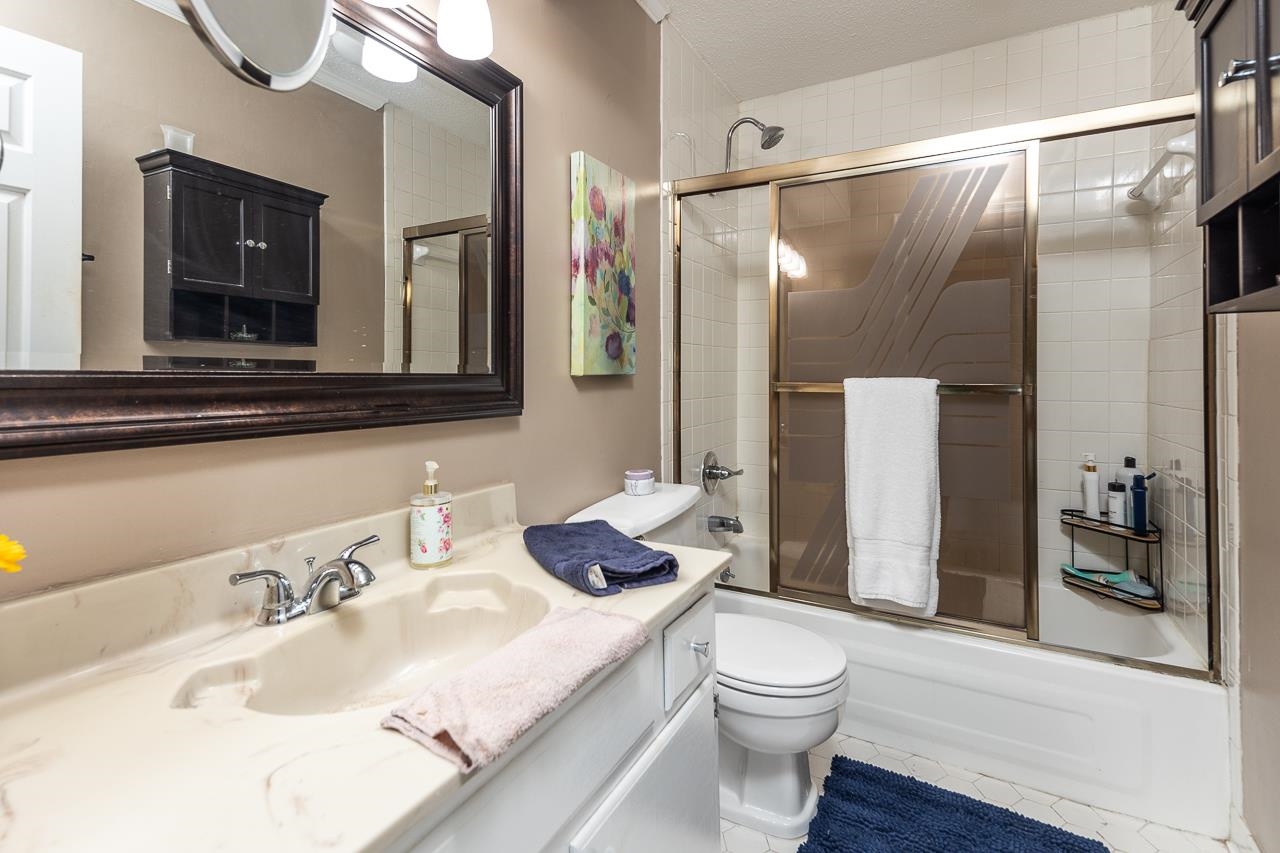 Full bathroom featuring combined bath / shower with glass door, vanity, toilet, and tile patterned floors