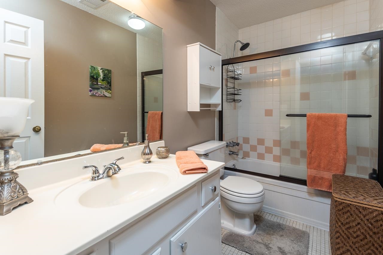 Full bathroom featuring tile patterned flooring, combined bath / shower with glass door, vanity, and toilet