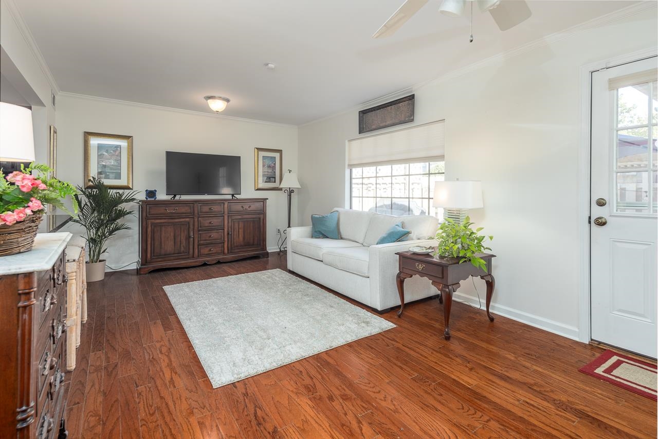 Living room featuring crown molding, ceiling fan, plenty of natural light, and dark hardwood / wood-style flooring