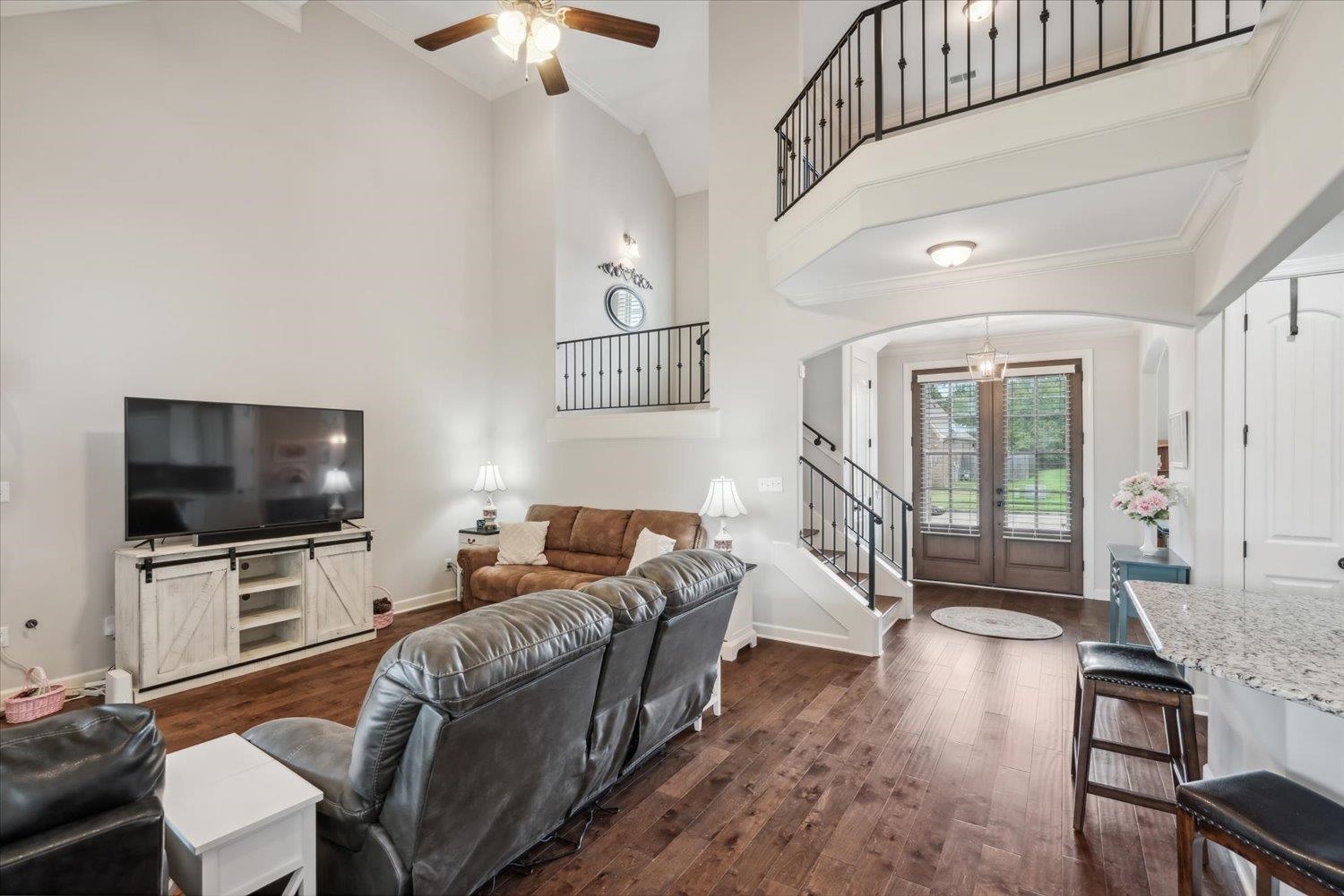 Living room with dark hardwood / wood-style floors, ceiling fan, and high vaulted ceiling