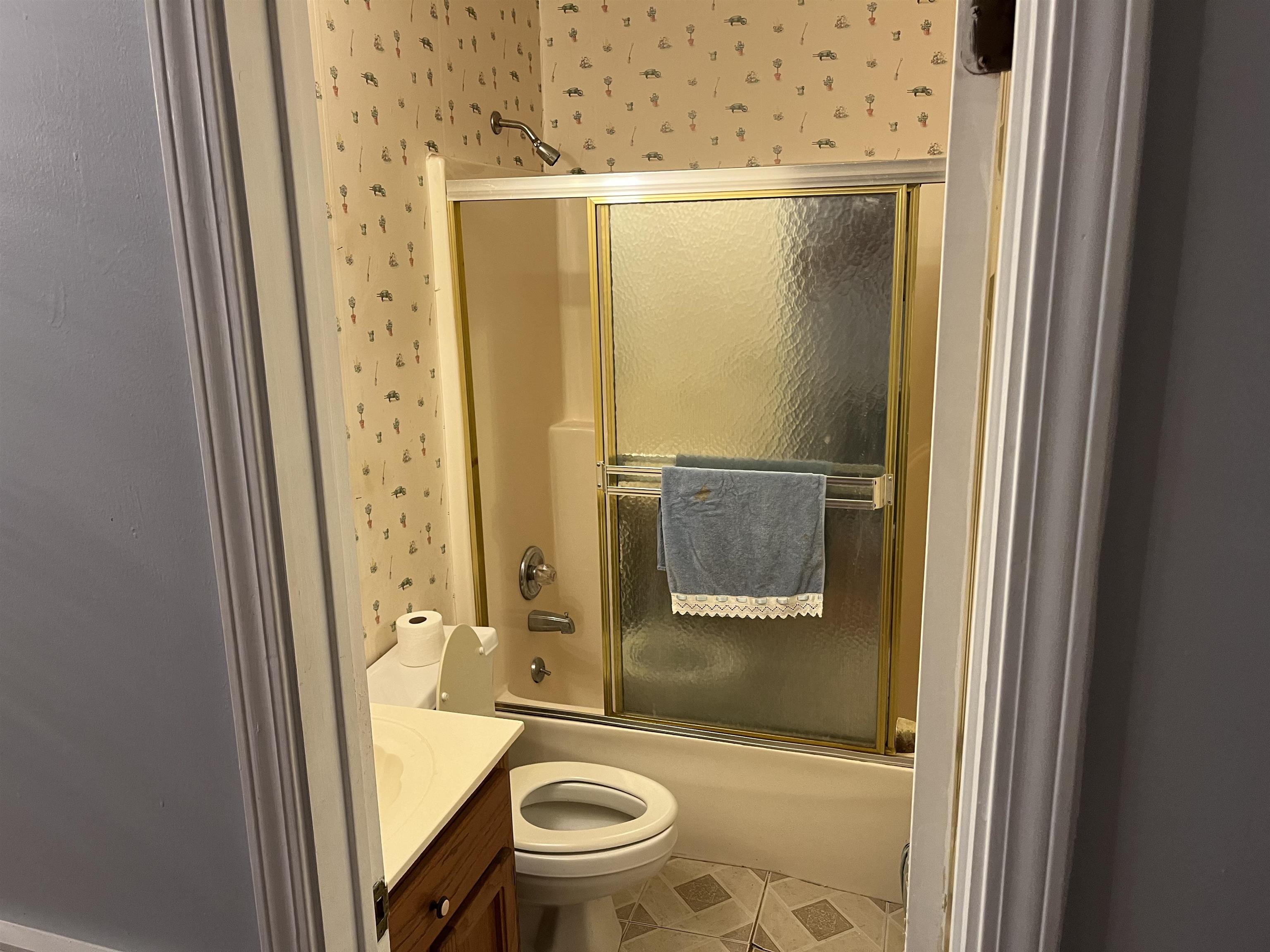 Full bathroom with tile patterned flooring, combined bath / shower with glass door, vanity, and toilet