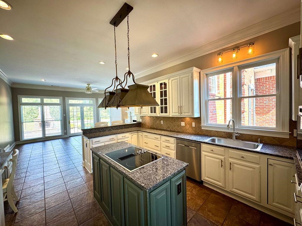 Kitchen featuring a kitchen island, green cabinetry, black electric stovetop, stainless steel dishwasher, and sink