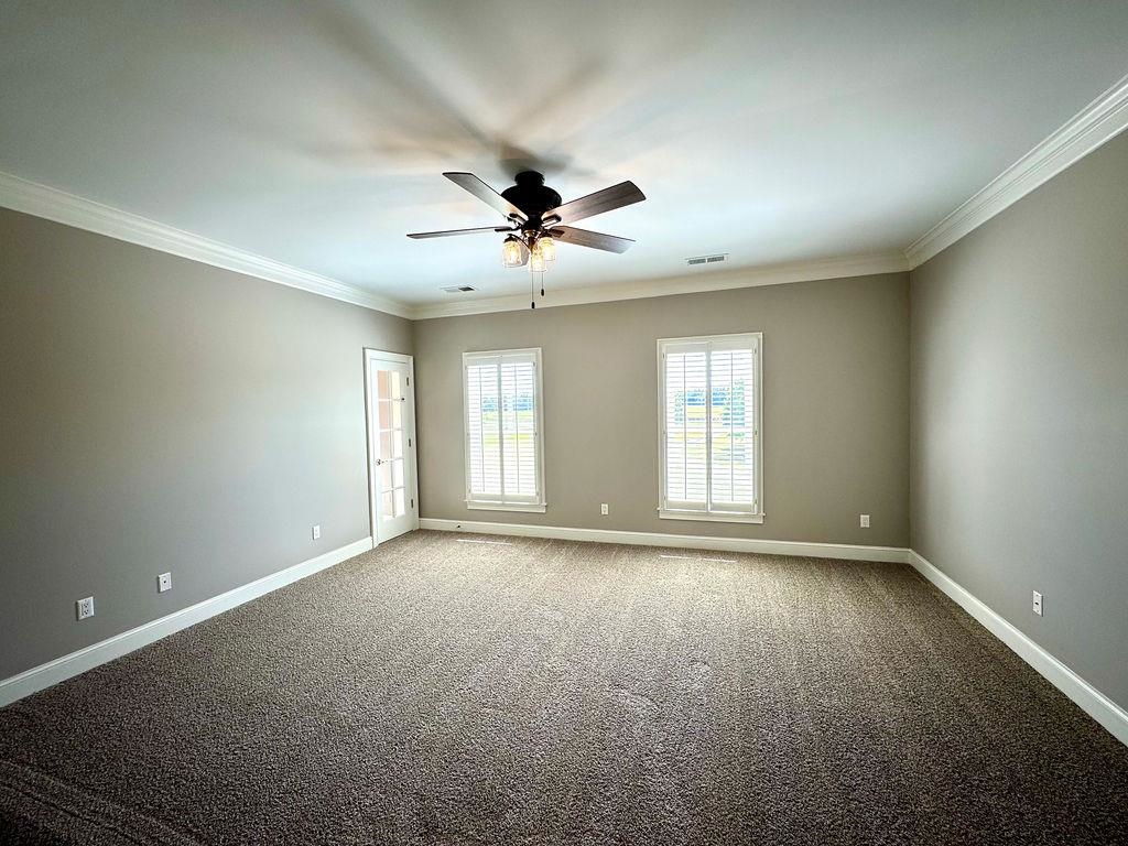 Carpeted spare room with ornamental molding and ceiling fan