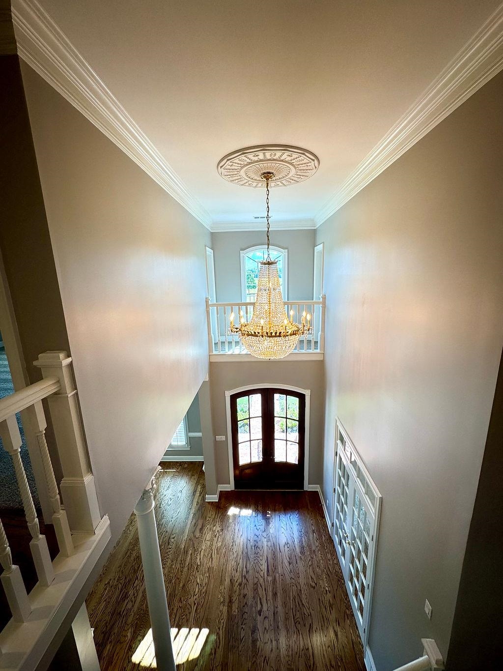 Entryway with an inviting chandelier, dark hardwood / wood-style floors, and crown molding