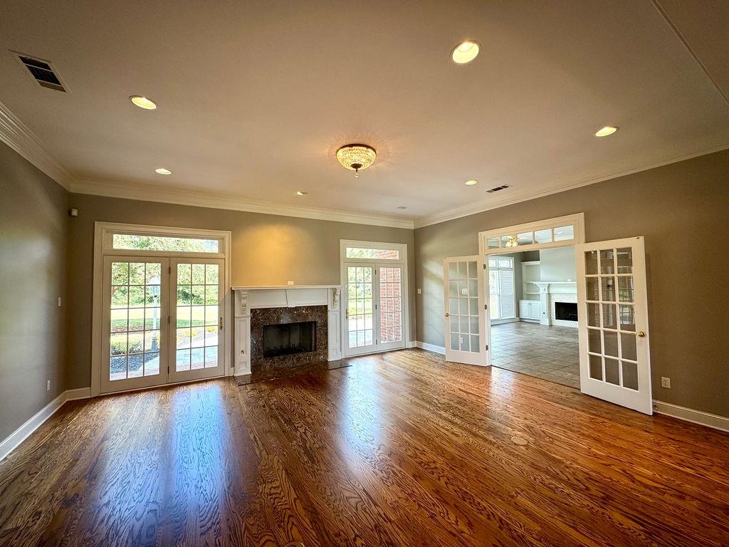 Unfurnished living room featuring ornamental molding, a high end fireplace, dark hardwood / wood-style floors, and french doors