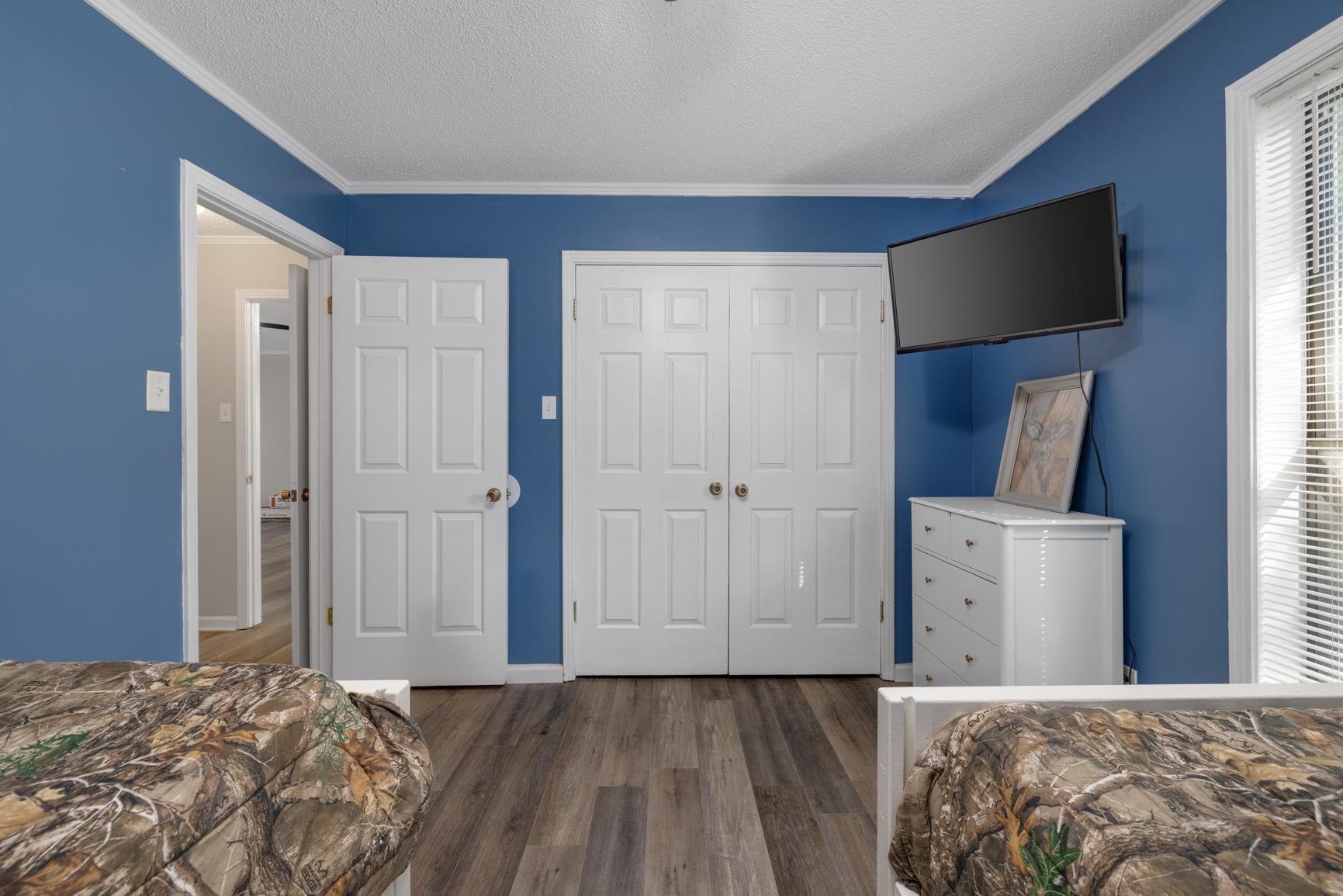 Bedroom featuring a textured ceiling, ornamental molding, dark hardwood / wood-style floors, and a closet