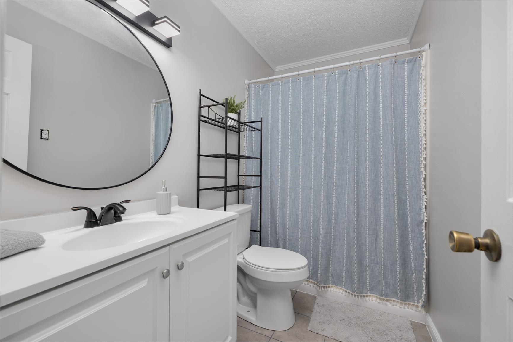 Bathroom featuring vanity, toilet, curtained shower, a textured ceiling, and tile patterned flooring