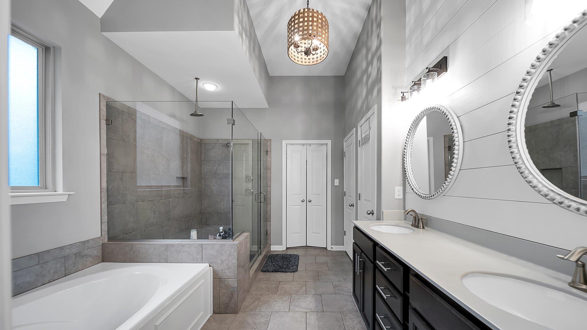 Bathroom featuring vanity, an inviting chandelier, and plus walk in shower