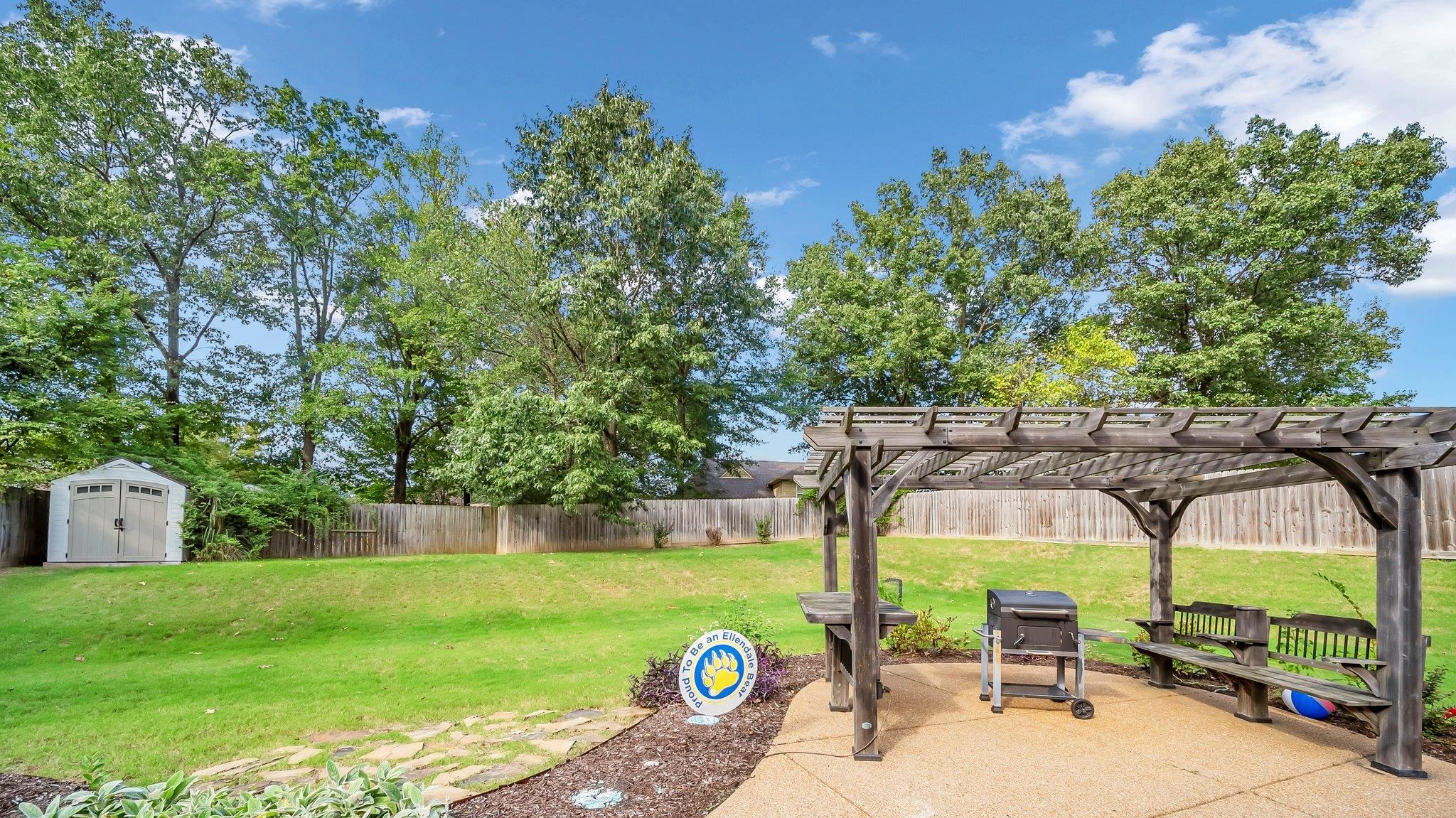 View of yard featuring a storage unit, a pergola, and a patio area