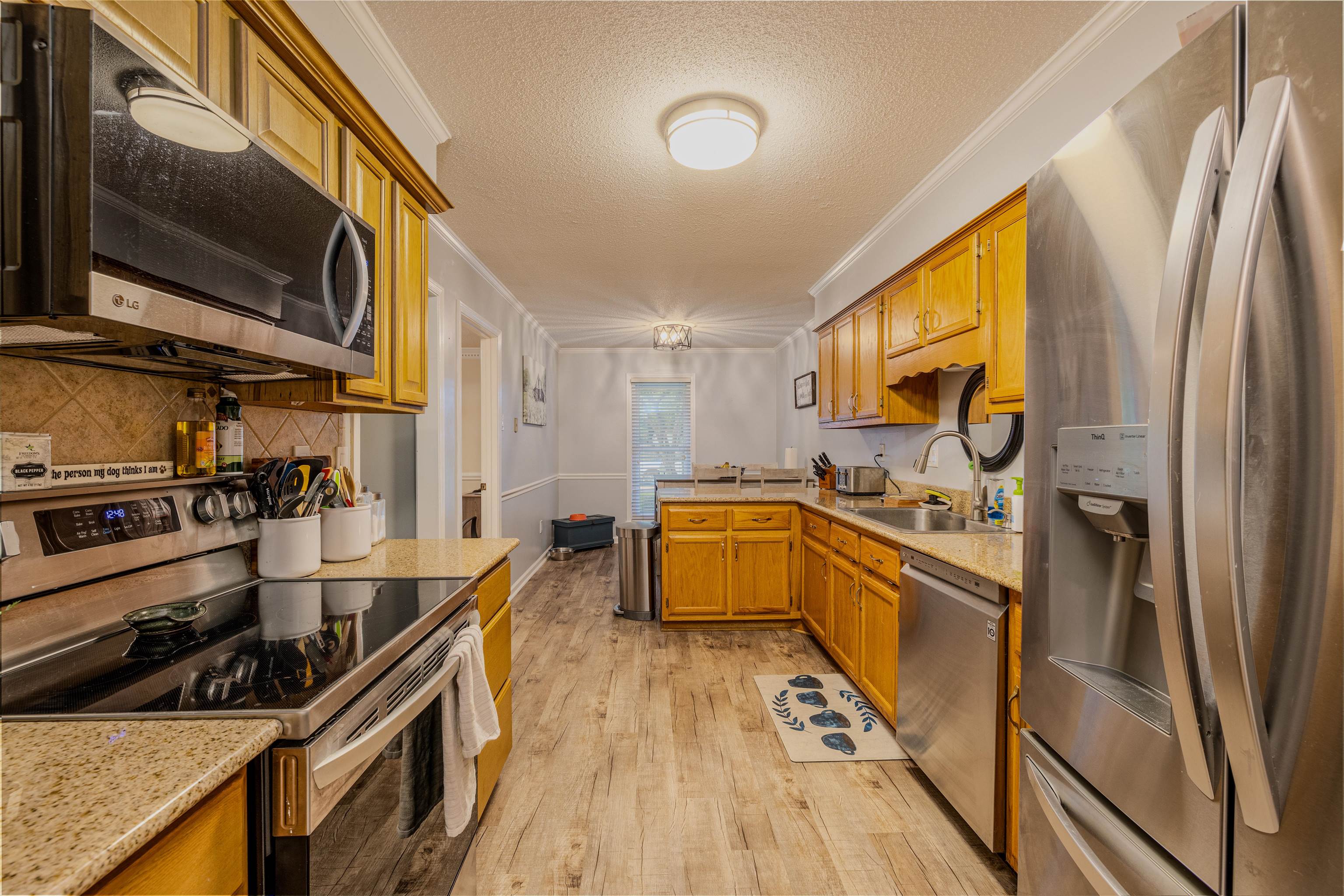 Kitchen with ornamental molding, sink, a textured ceiling, stainless steel appliances, and light wood-type flooring