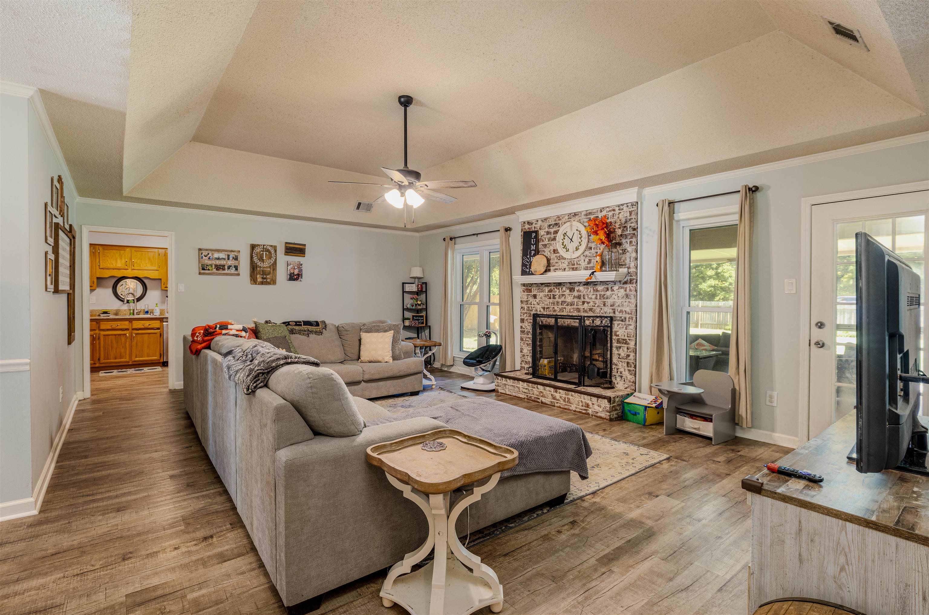 Living room featuring a brick fireplace, a wealth of natural light, ceiling fan, and light wood-type flooring