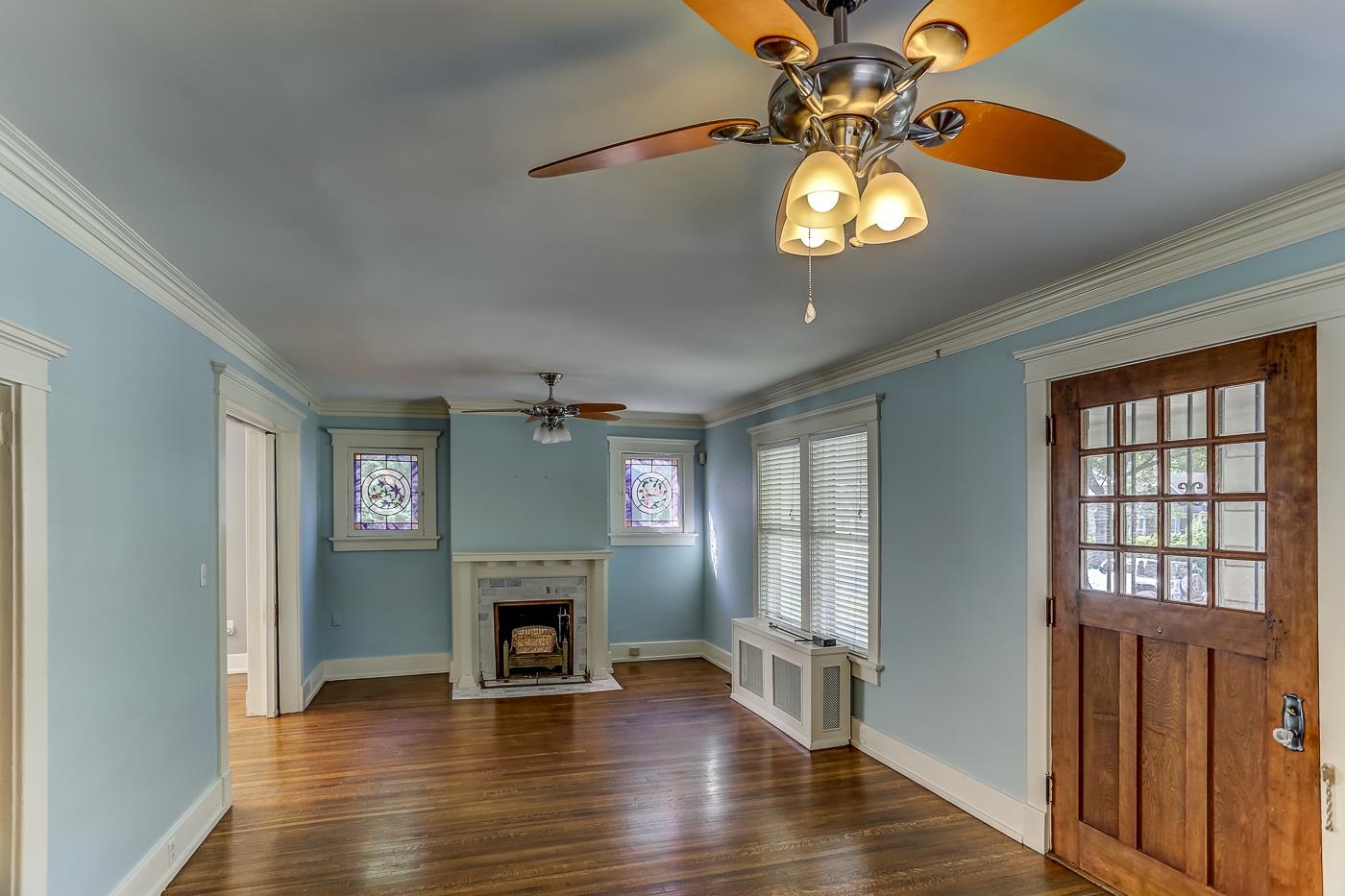 Unfurnished living room featuring dark wood-type flooring, ceiling fan, a fireplace, and crown molding