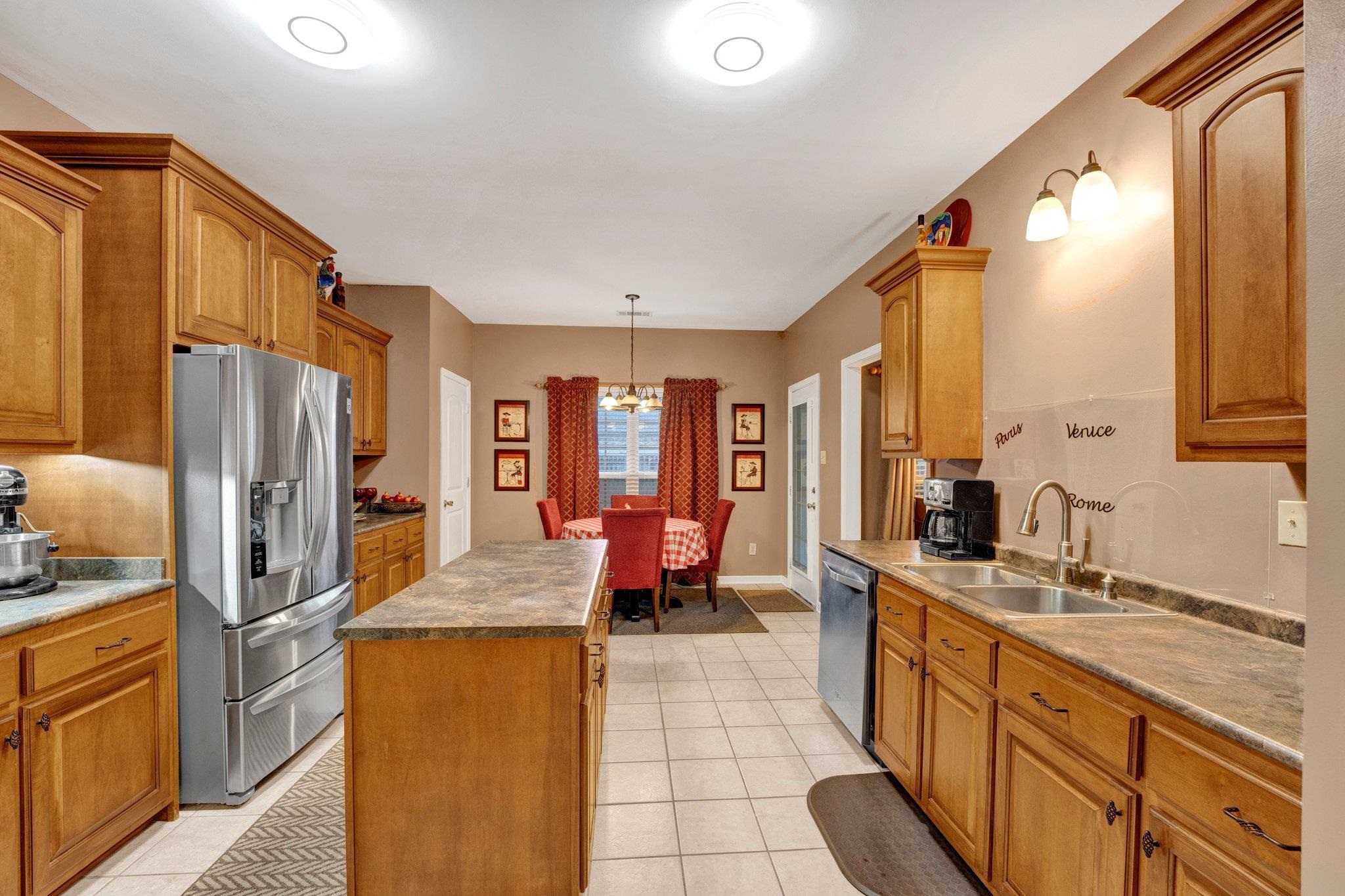 Kitchen featuring stainless steel appliances, light tile patterned floors, a kitchen island, and sink