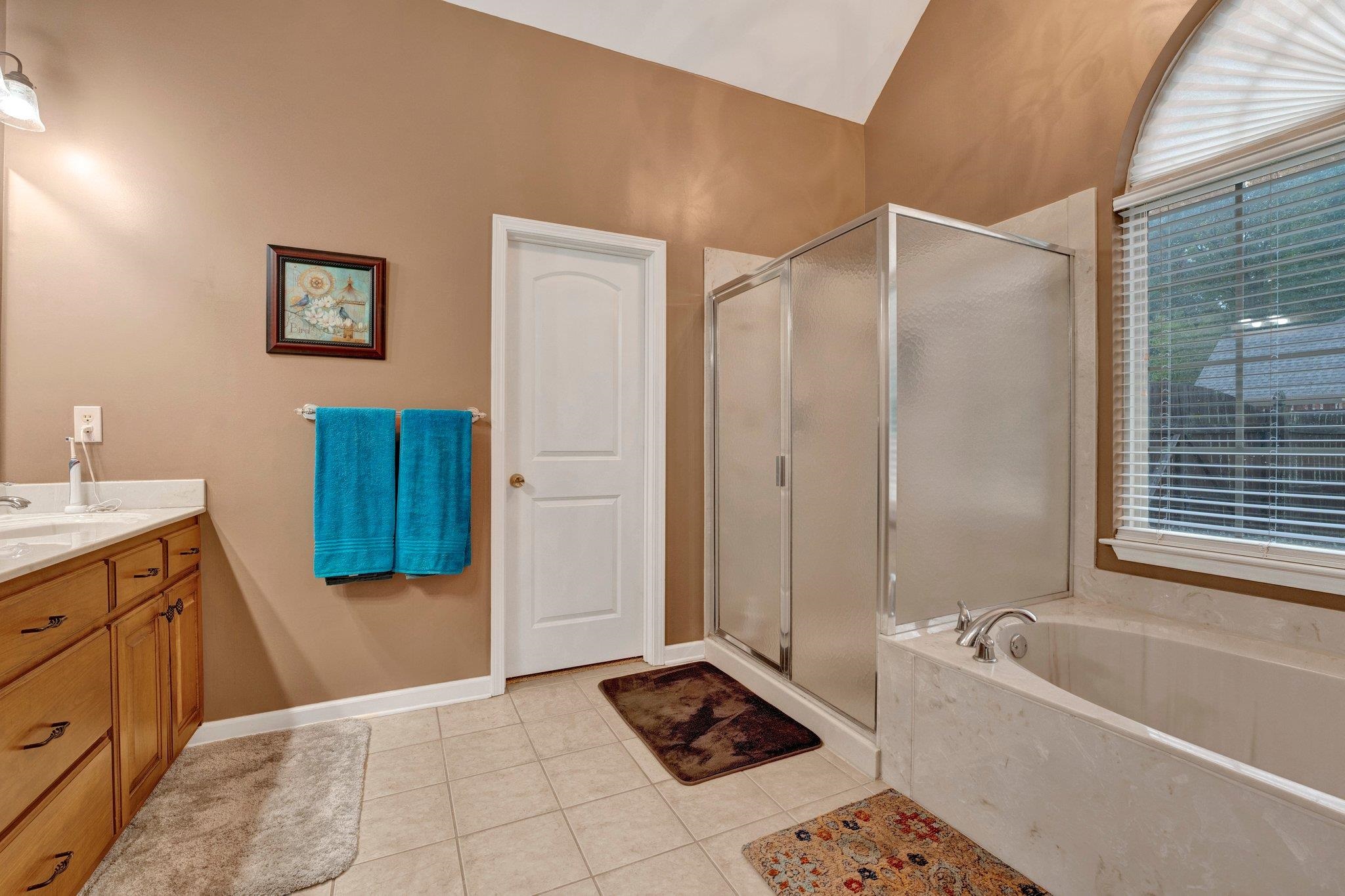 Bathroom with tile patterned flooring, vanity, and separate shower and tub