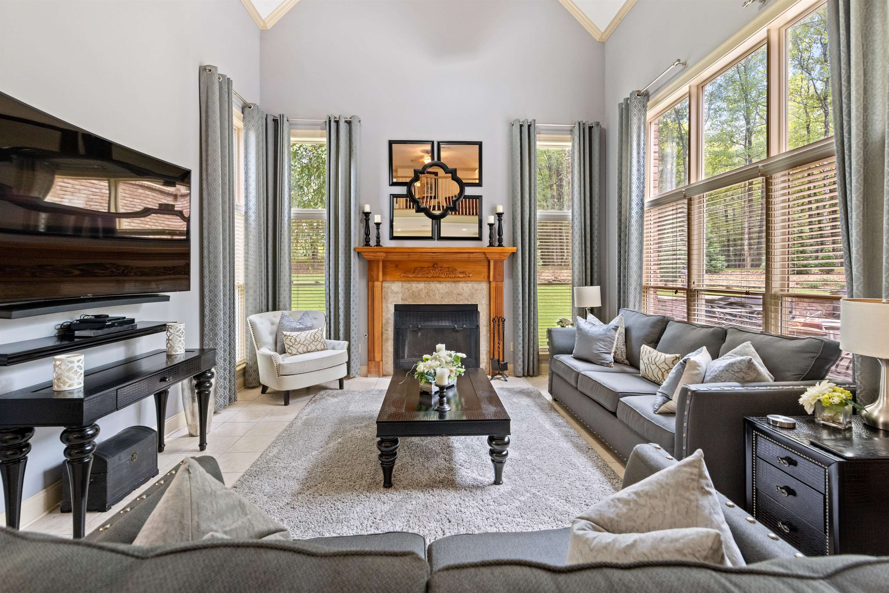 Living room with a fireplace, ornamental molding, high vaulted ceiling, and a wealth of natural light