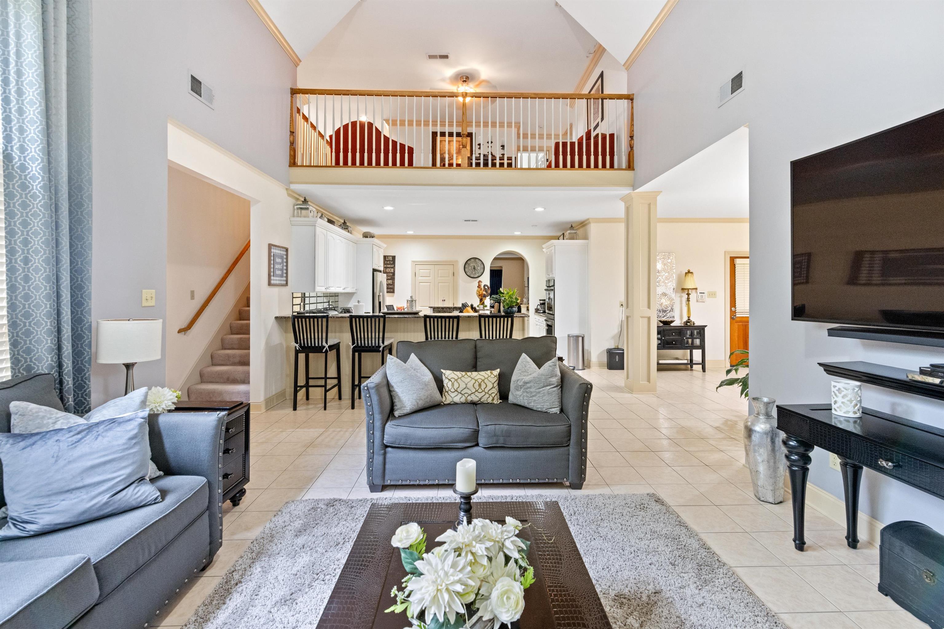 Tiled living room featuring ornamental molding and high vaulted ceiling