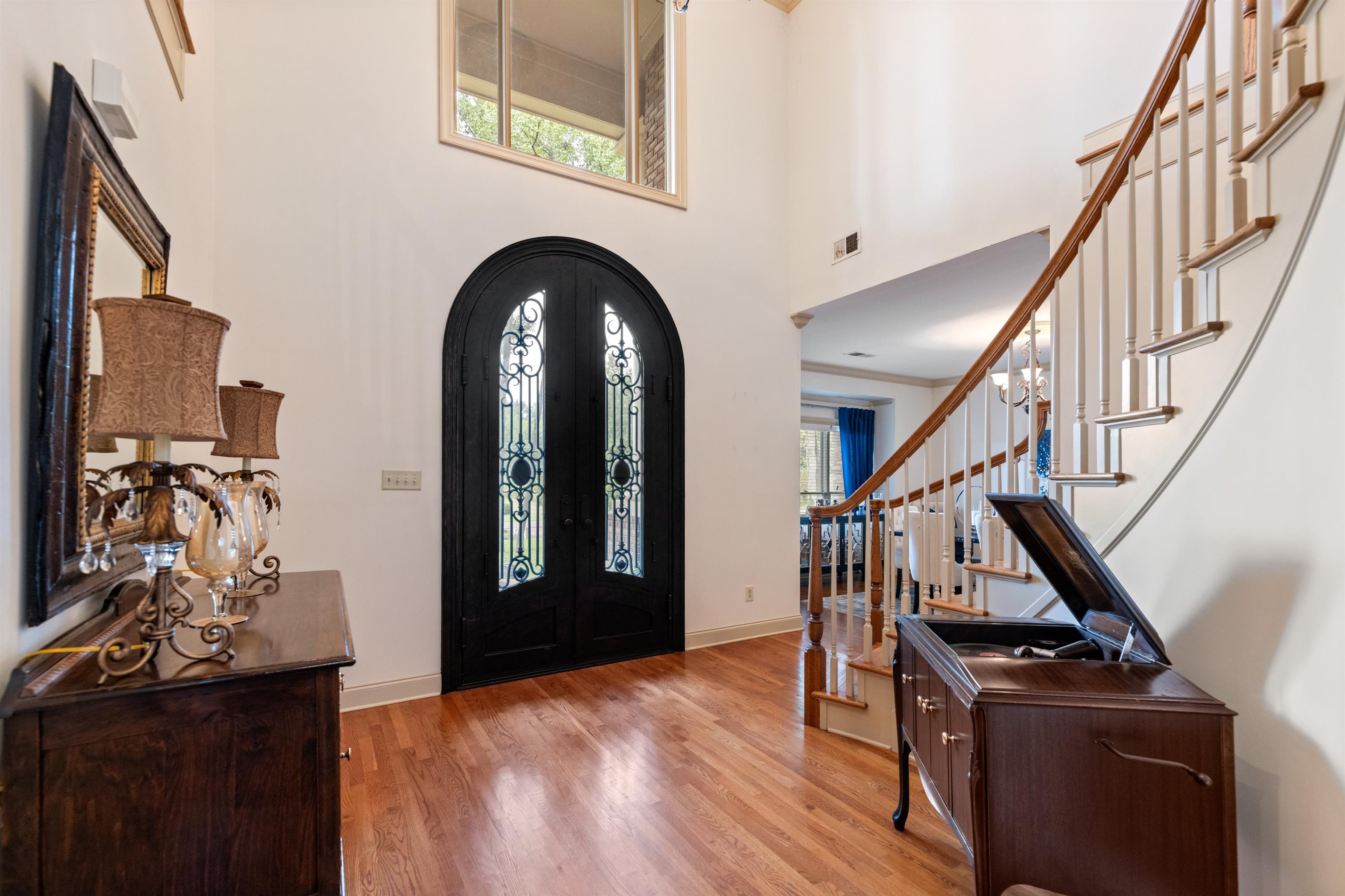 Entrance foyer with ornamental molding, a towering ceiling, light wood-type flooring, and a healthy amount of sunlight