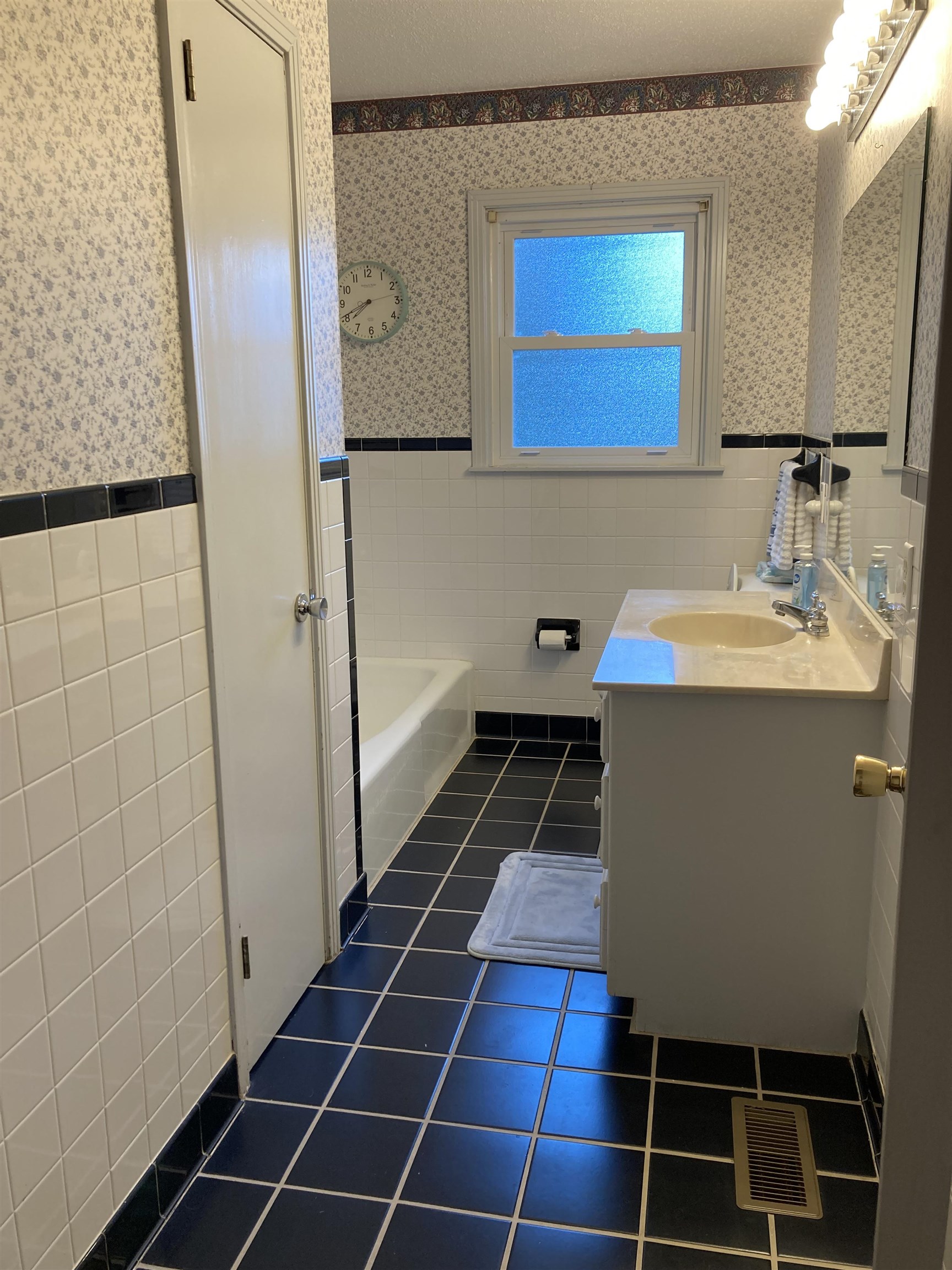 Bathroom featuring vanity, tile walls, tile patterned flooring, and a tub