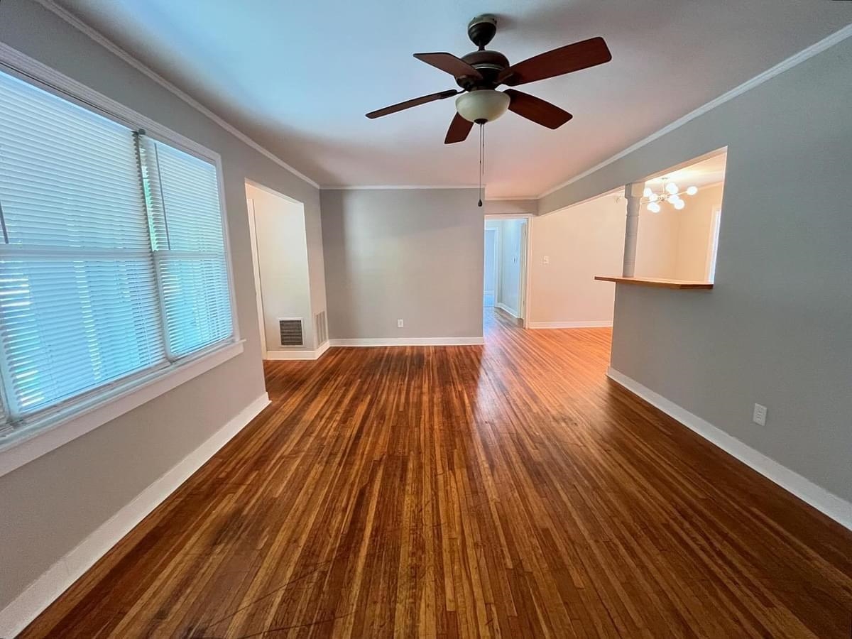 Living room featuring ceiling fan with notable chandelier, hardwood / wood-style floors, and crown molding