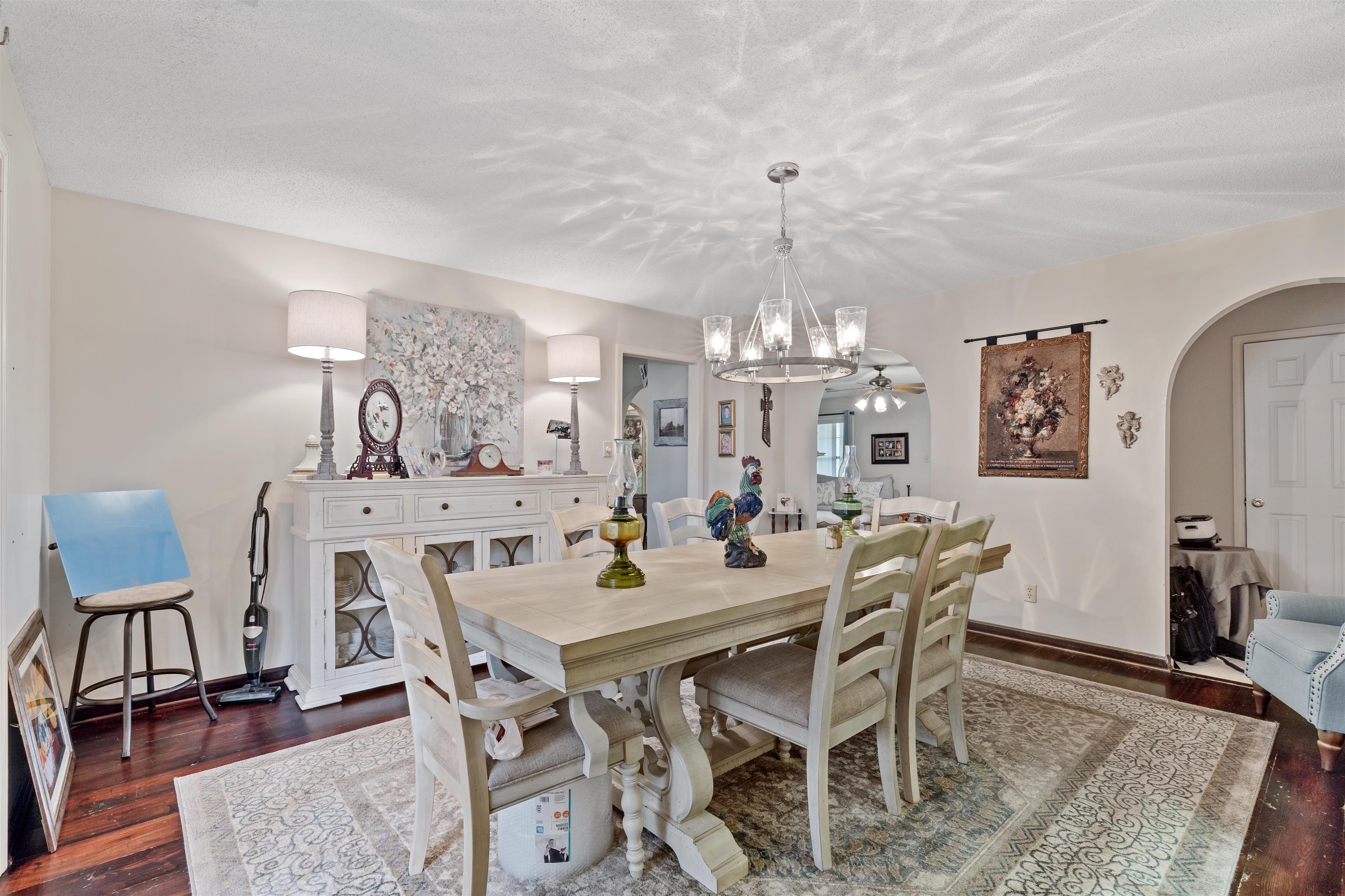 Dining space with a textured ceiling, an inviting chandelier, and dark wood-type flooring