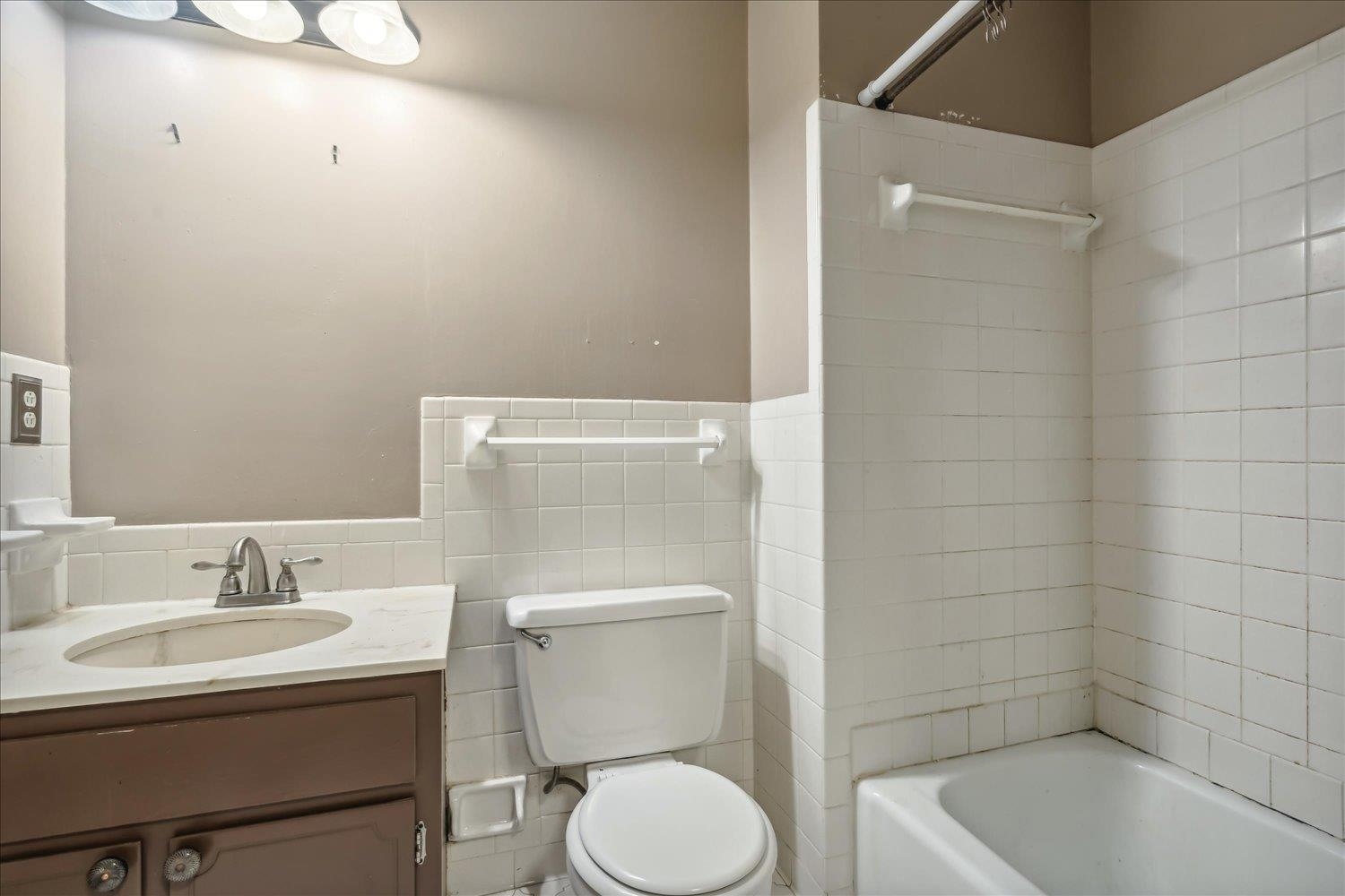 Full bathroom with tile walls, shower / bathtub combination, vanity, and toilet