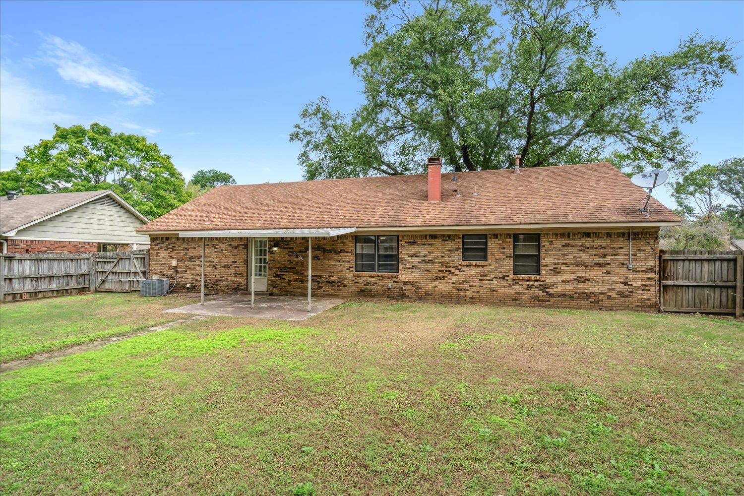 Rear view of house with central AC unit, a lawn, and a patio